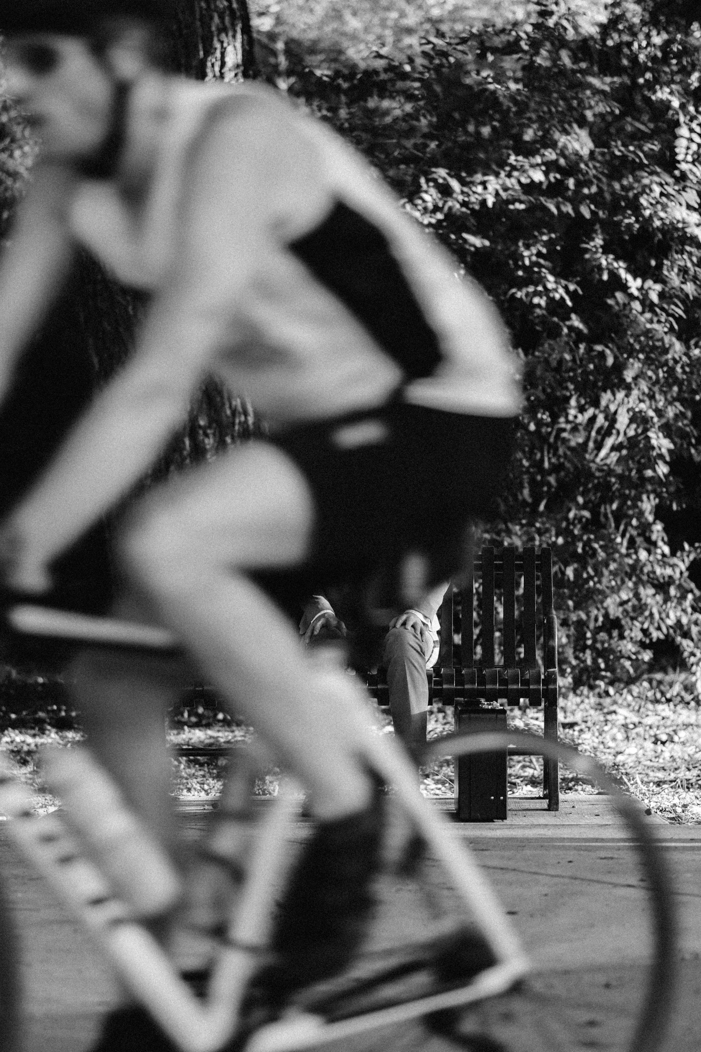 A biker going in front of a person in a suit on a park bench. About that Promotion from Jonathan Grado's Happy Hour series.