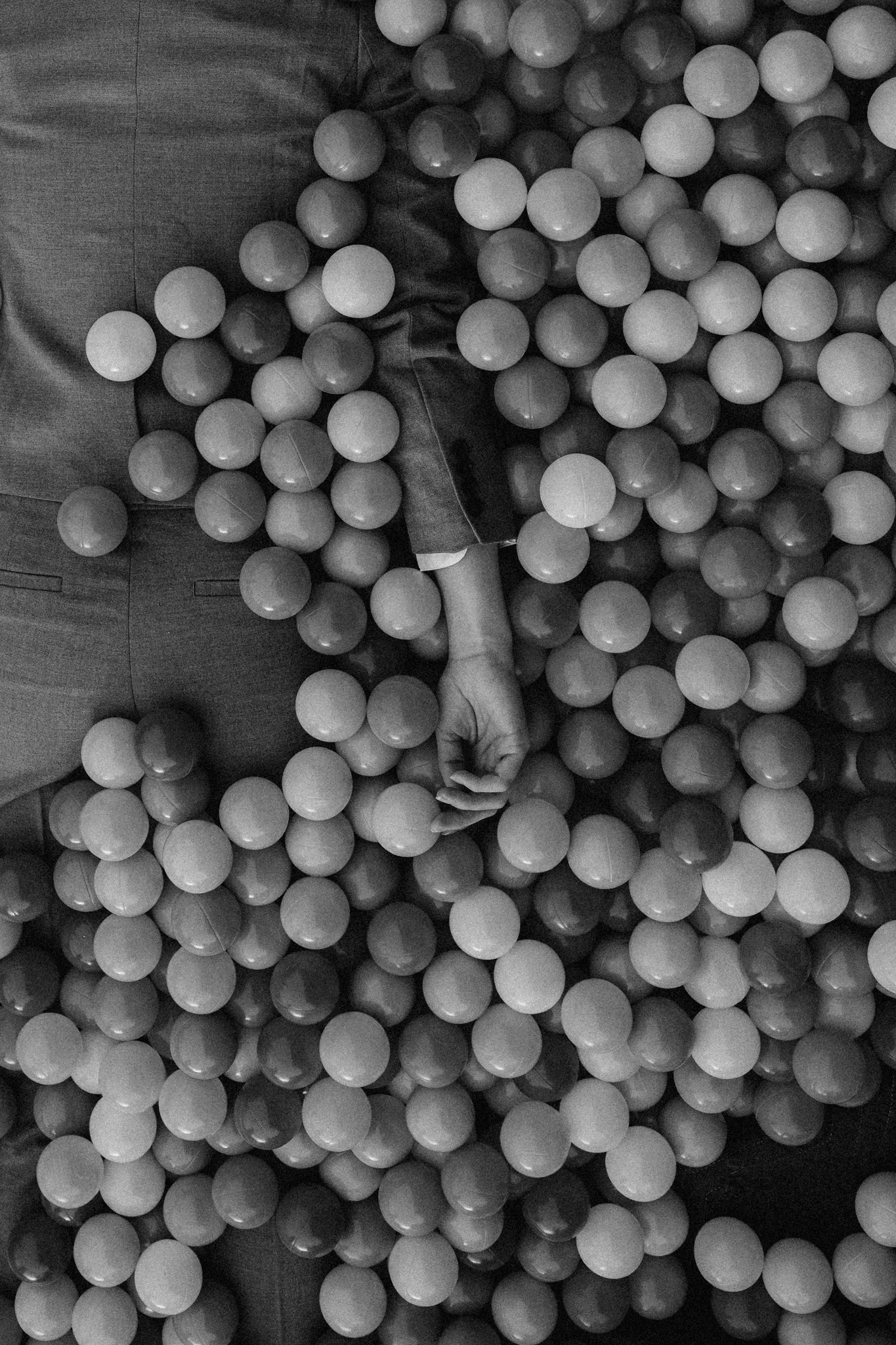 A person in a suit sinking in a ball pit. Graveyard Shift from Jonathan Grado's Happy Hour series.