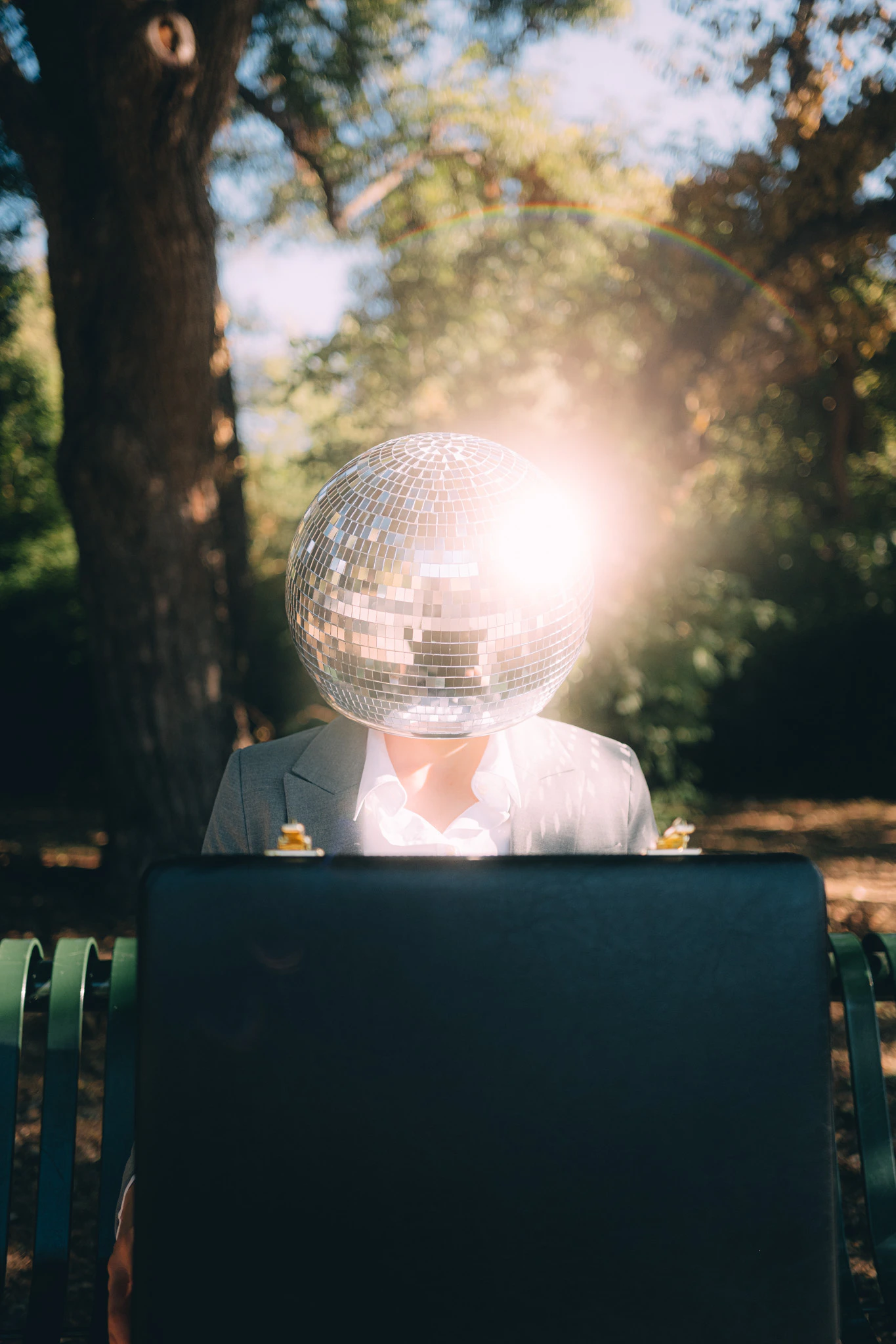 Sunlight reflecting off a businessperson's disco ball head. Outlook from Jonathan Grado's Happy Hour series.