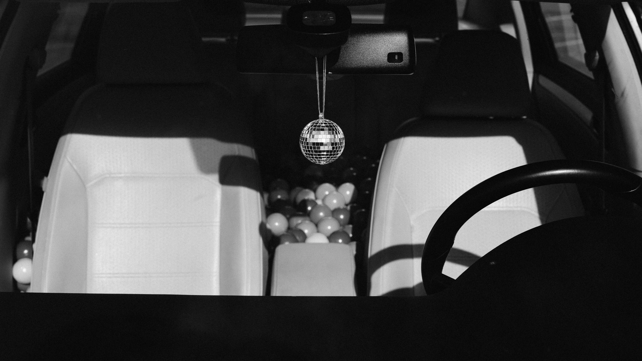 Car filled with a ball pit and a small disco ball rearview ornament. Toll Free from Jonathan Grado's Happy Hour series.