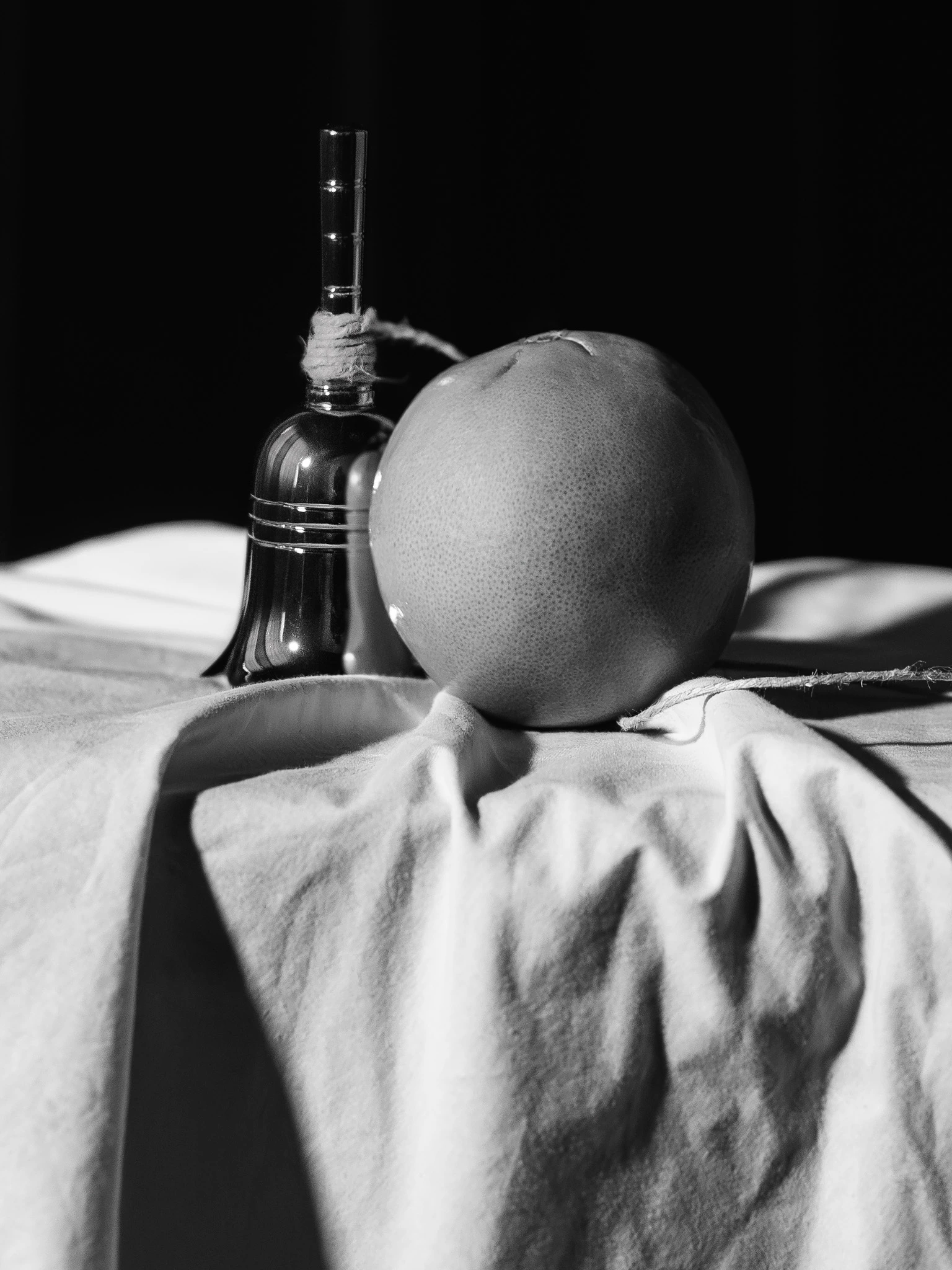 Small hand bell and an orange connected by a string. Formation of Thought #01 from Jonathan Grado's Saint Citrus series.