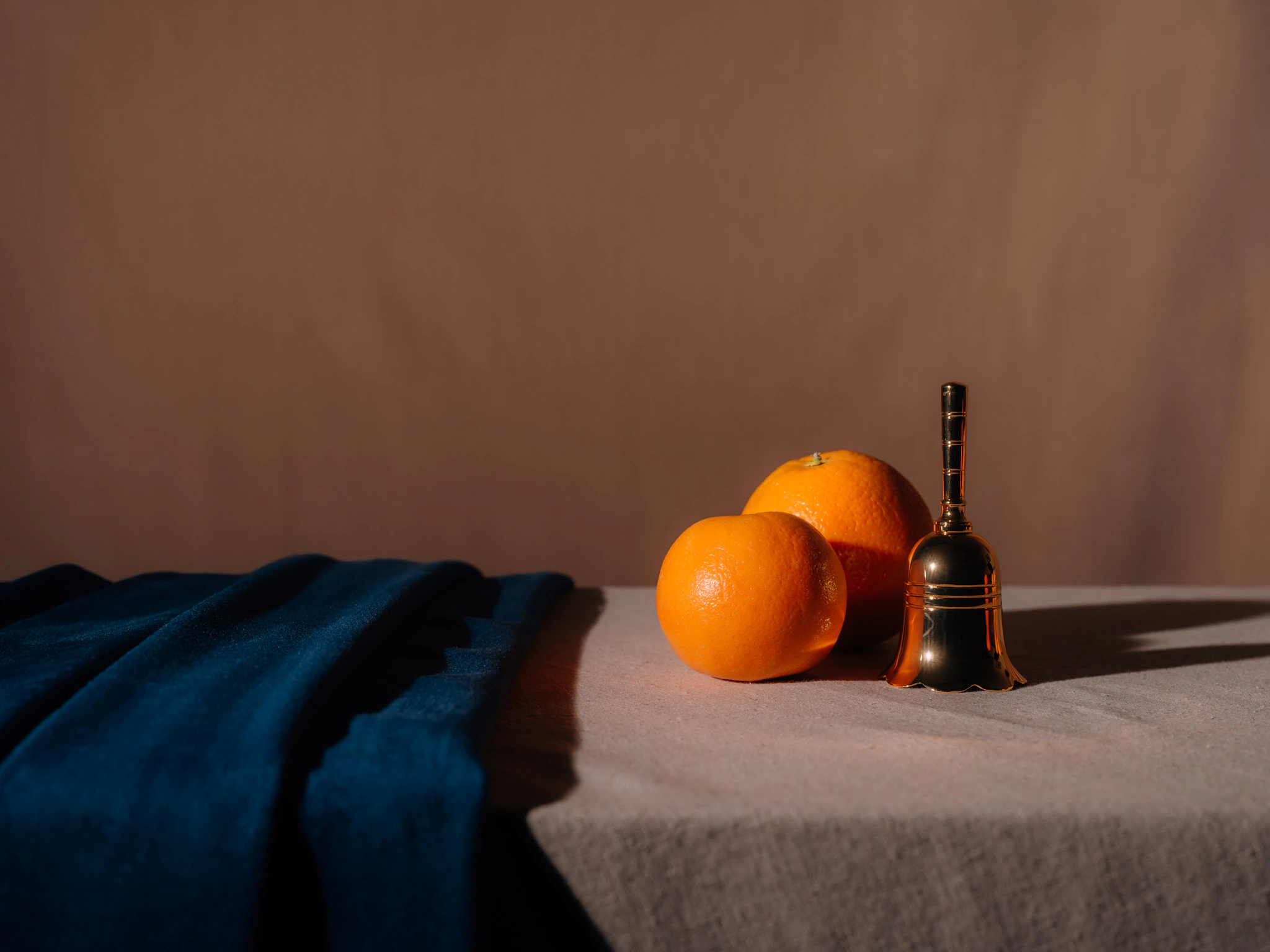 Two oranges with a small bell with blue and beige velvet. The Shape of Thought from Jonathan Grado's Saint Citrus series.