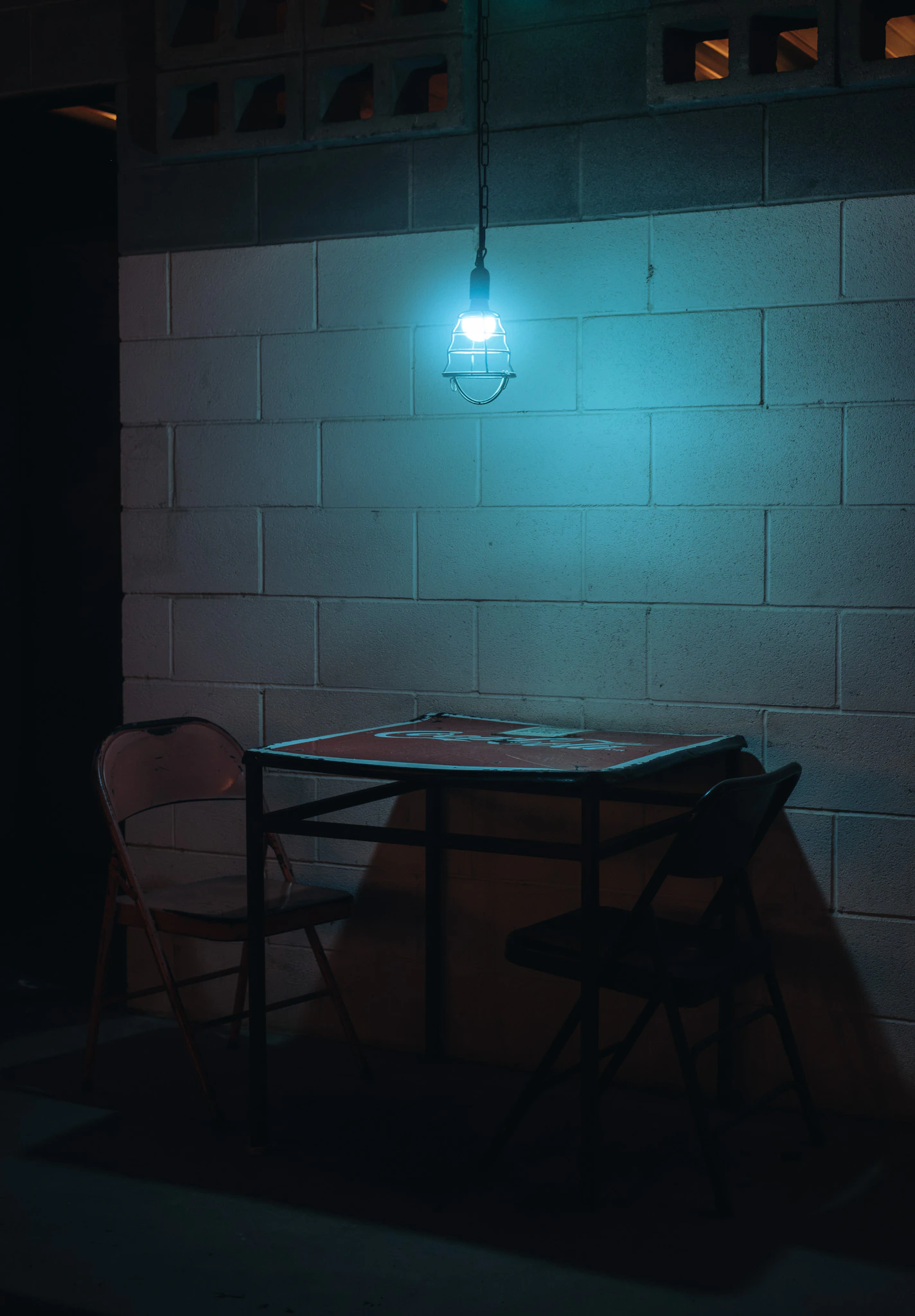 Empty chairs at night under a single blue light in Austin. Blue Light Therapy from Jonathan Grado's Provided You're Still Here series.