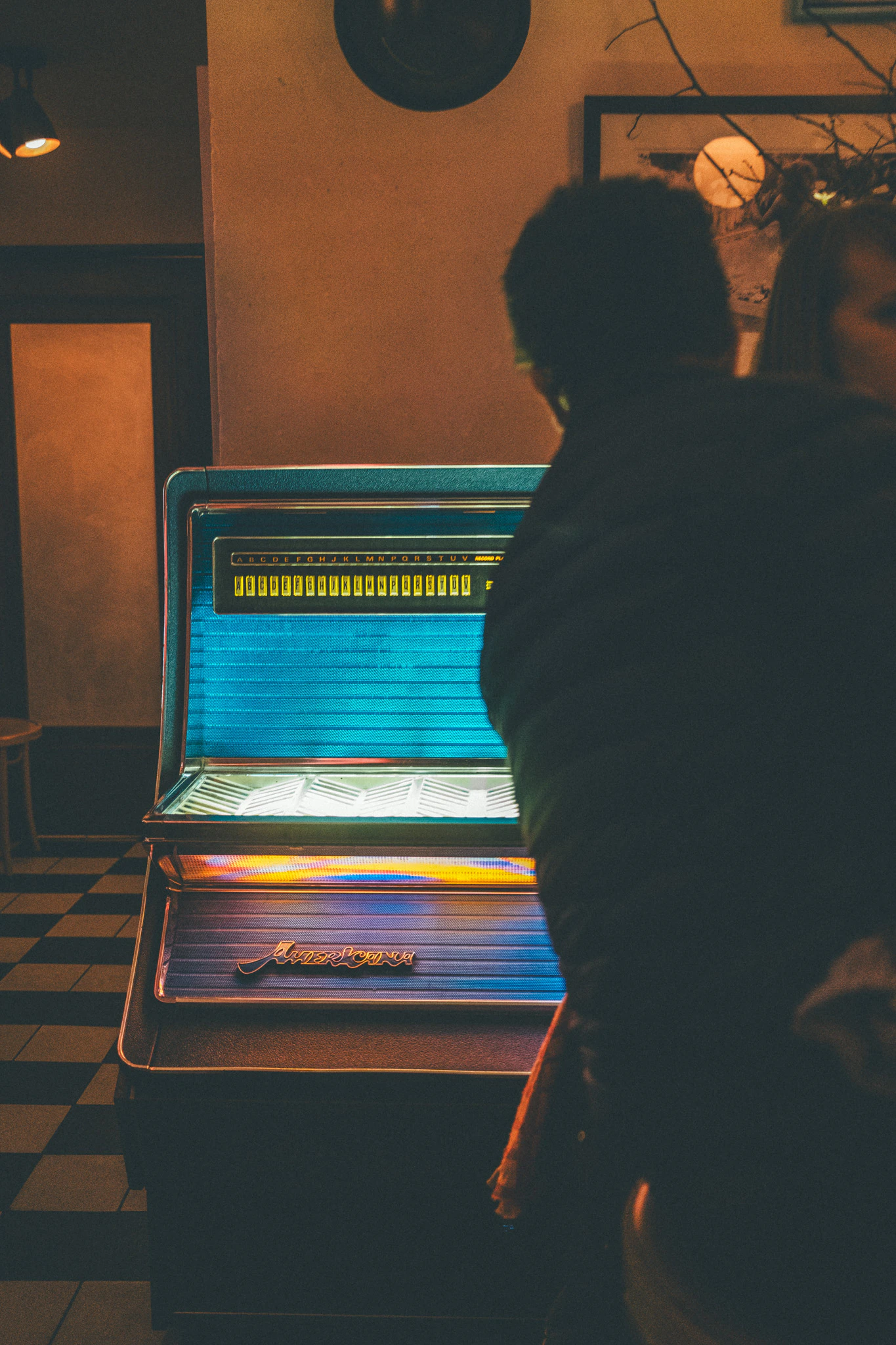 Man in front of a colorful jukebox at a bar at night. Meet Me at Track Three from Jonathan Grado's Provided You're Still Here series.