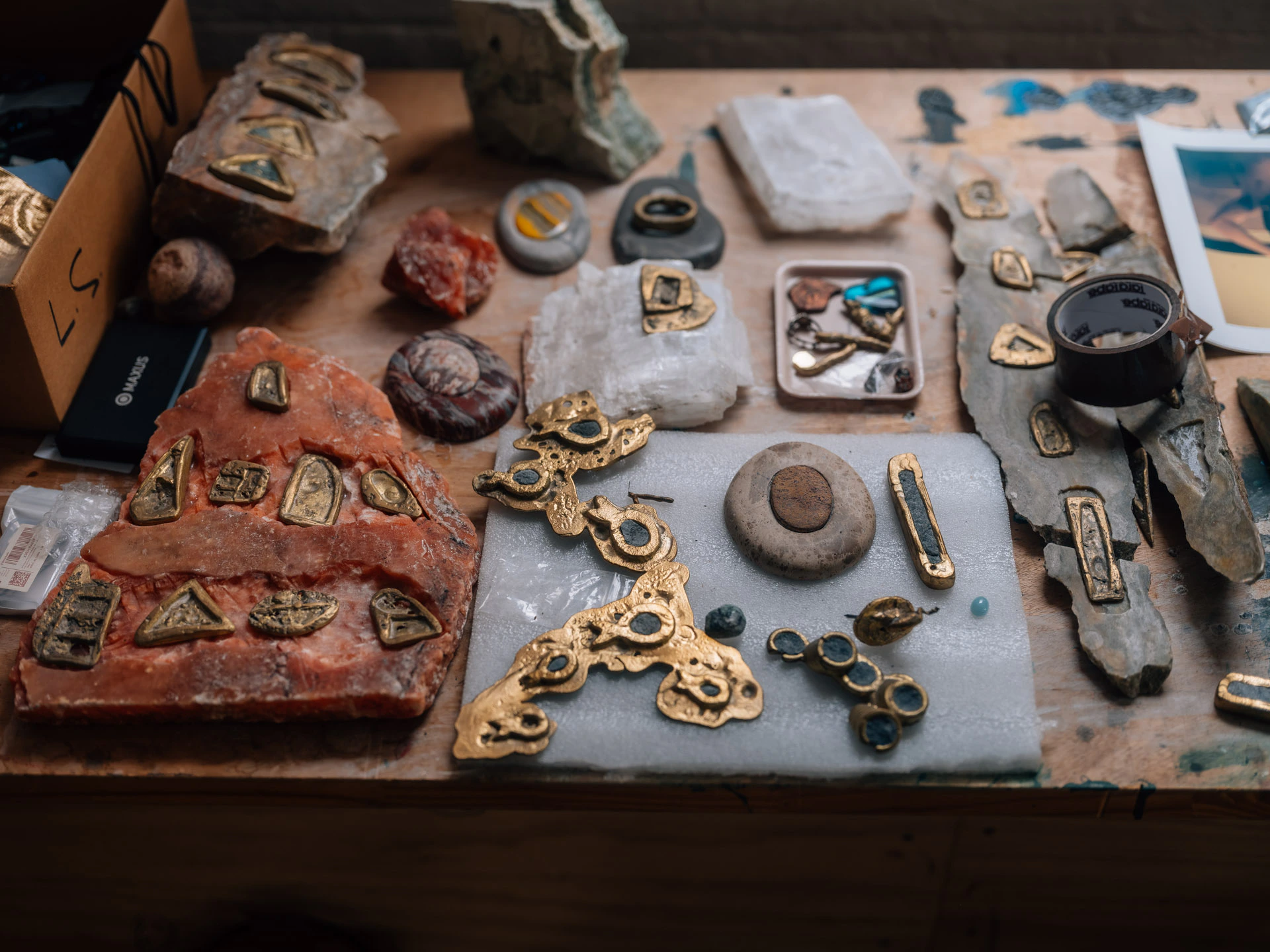 desk filled with rocks, art, and metalworks in Lara Saget's studio