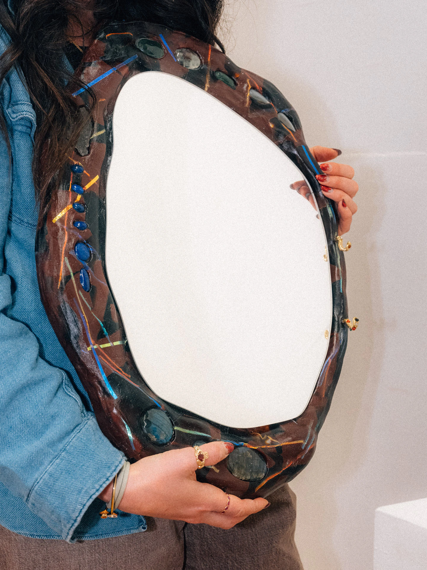 Lara Saget holding mirror artwork in her Brooklyn studio