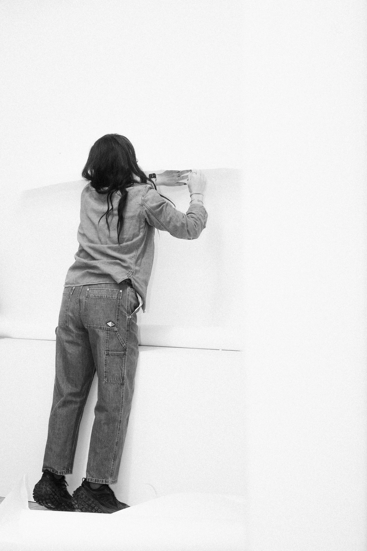Lara Saget putting up artwork in studio