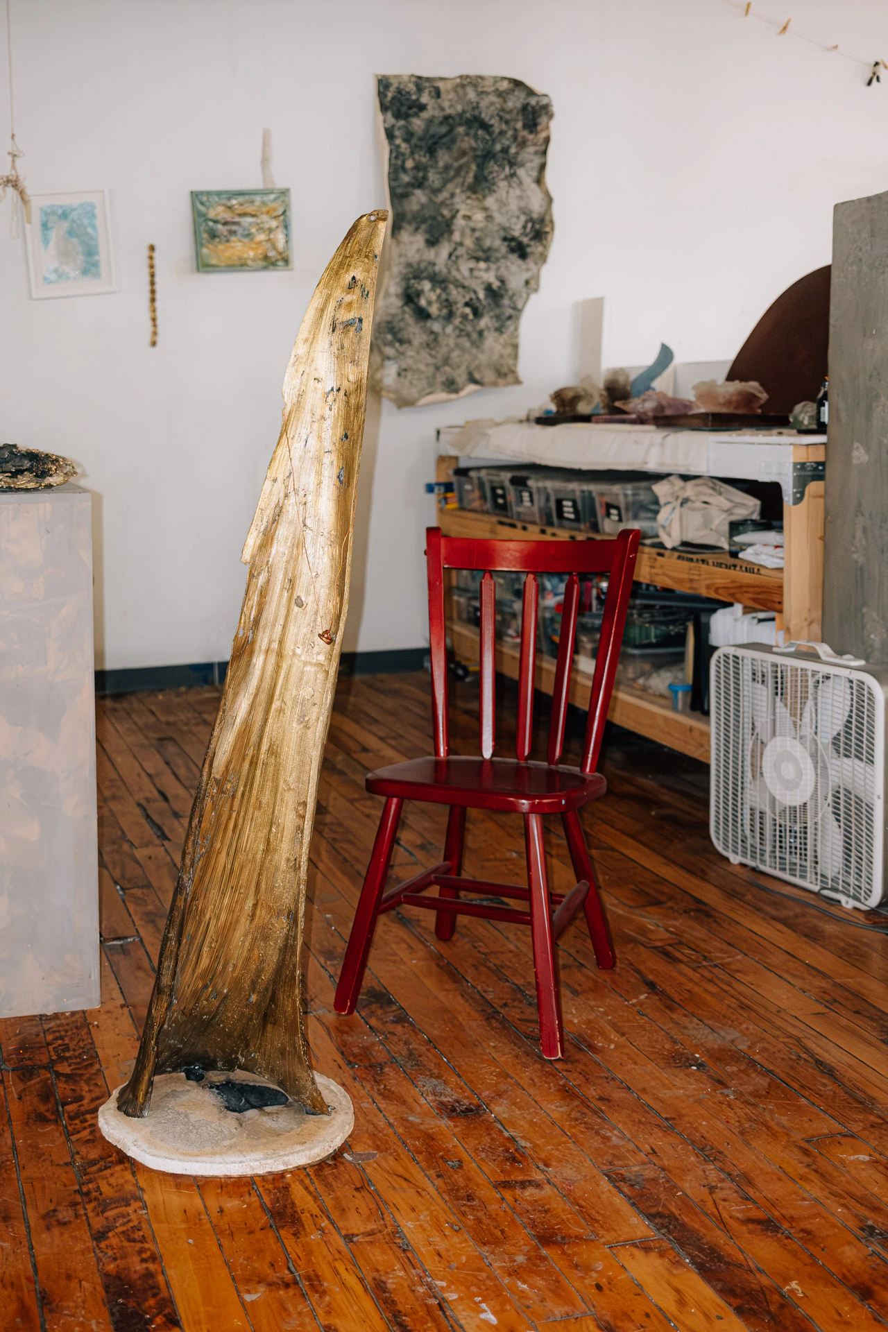 metalwork bronze palm leaf with red chair and floor fan in Lara Saget's Brooklyn studio