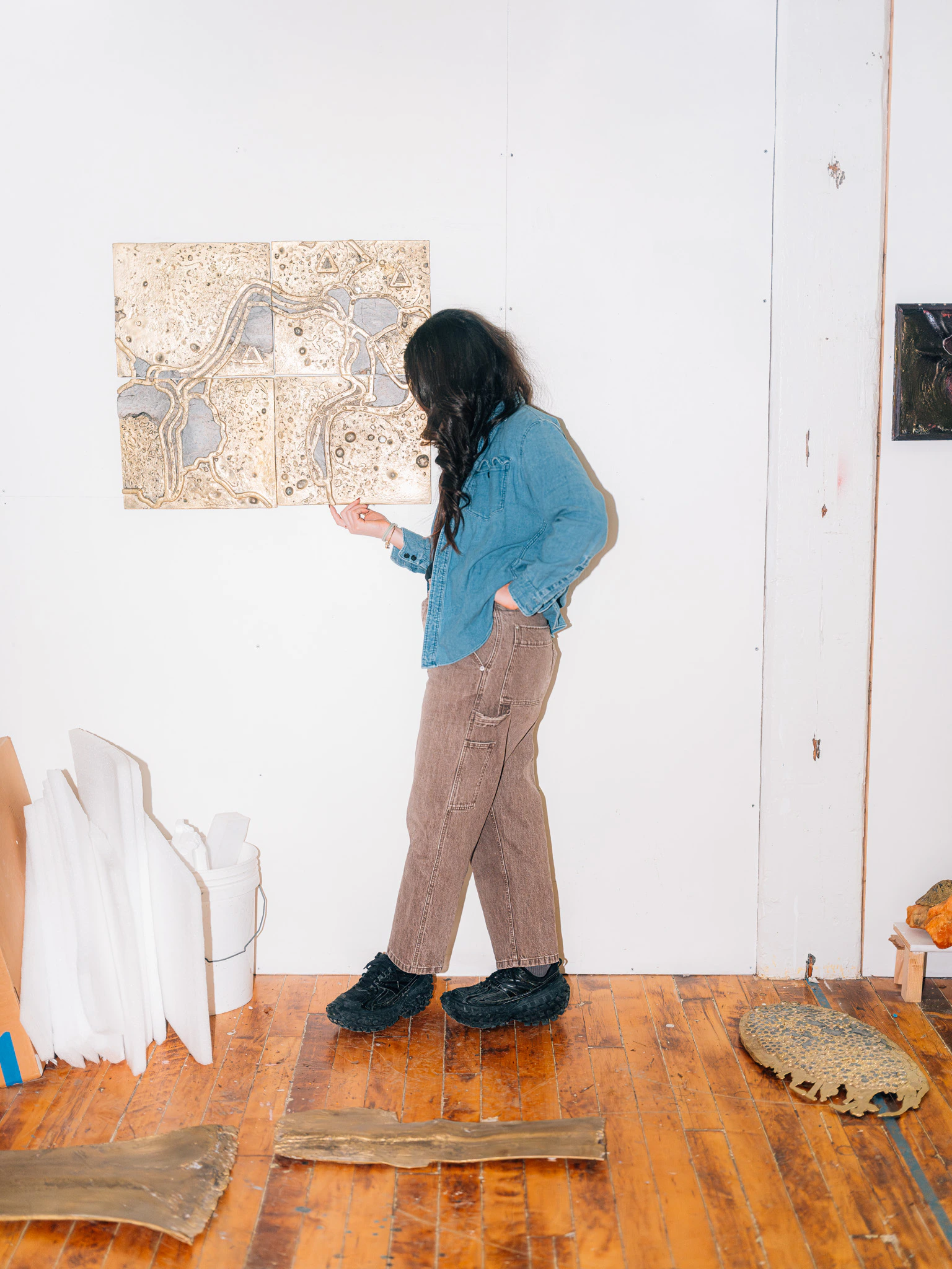Lara Saget standing with her sculptures in her studio using hard flash photography