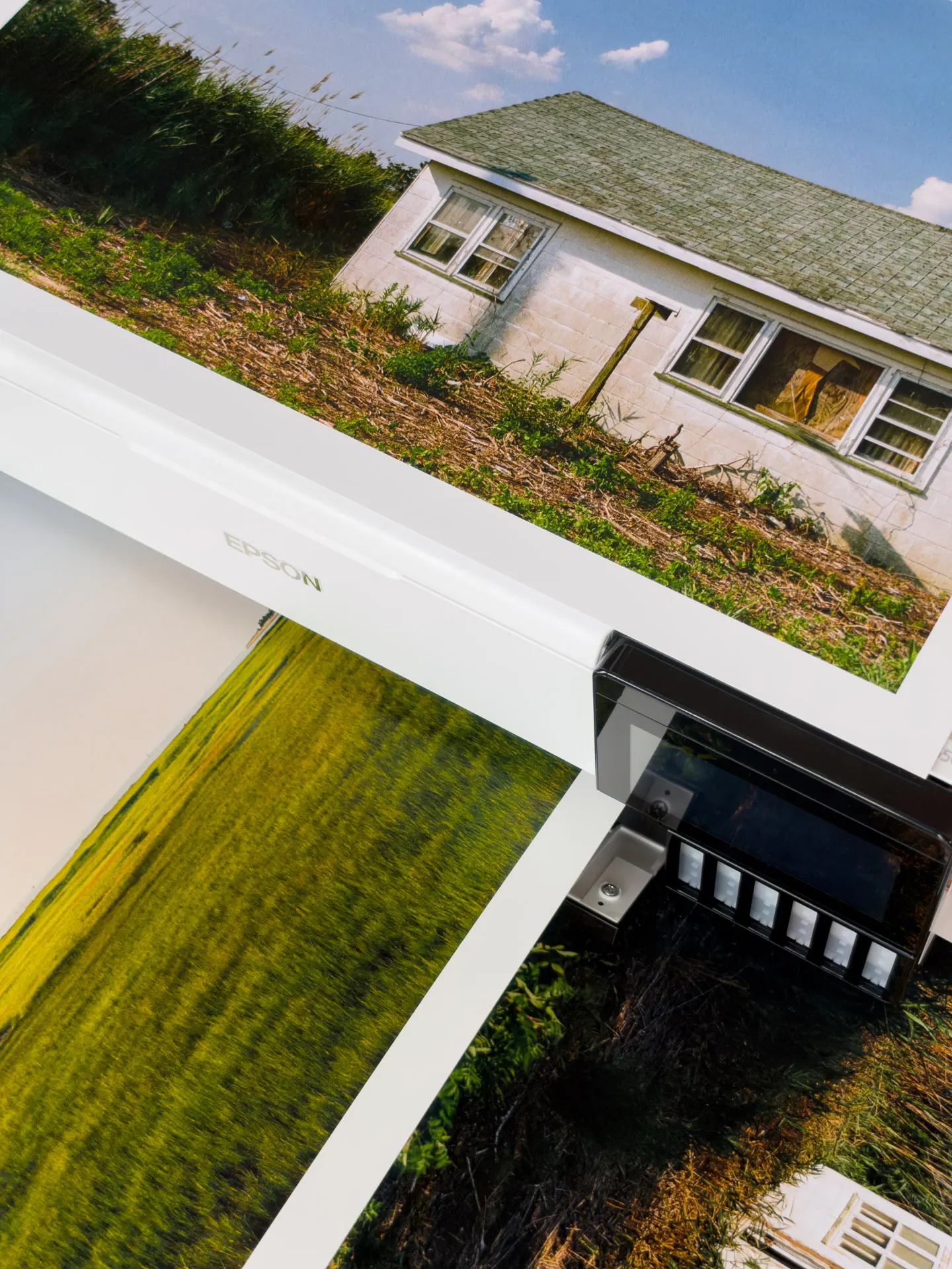 Three 13x19 film prints on an Epson ET-8550: a white house on top of the printer, a green field in the tray, and a white window frame in tall grass below.