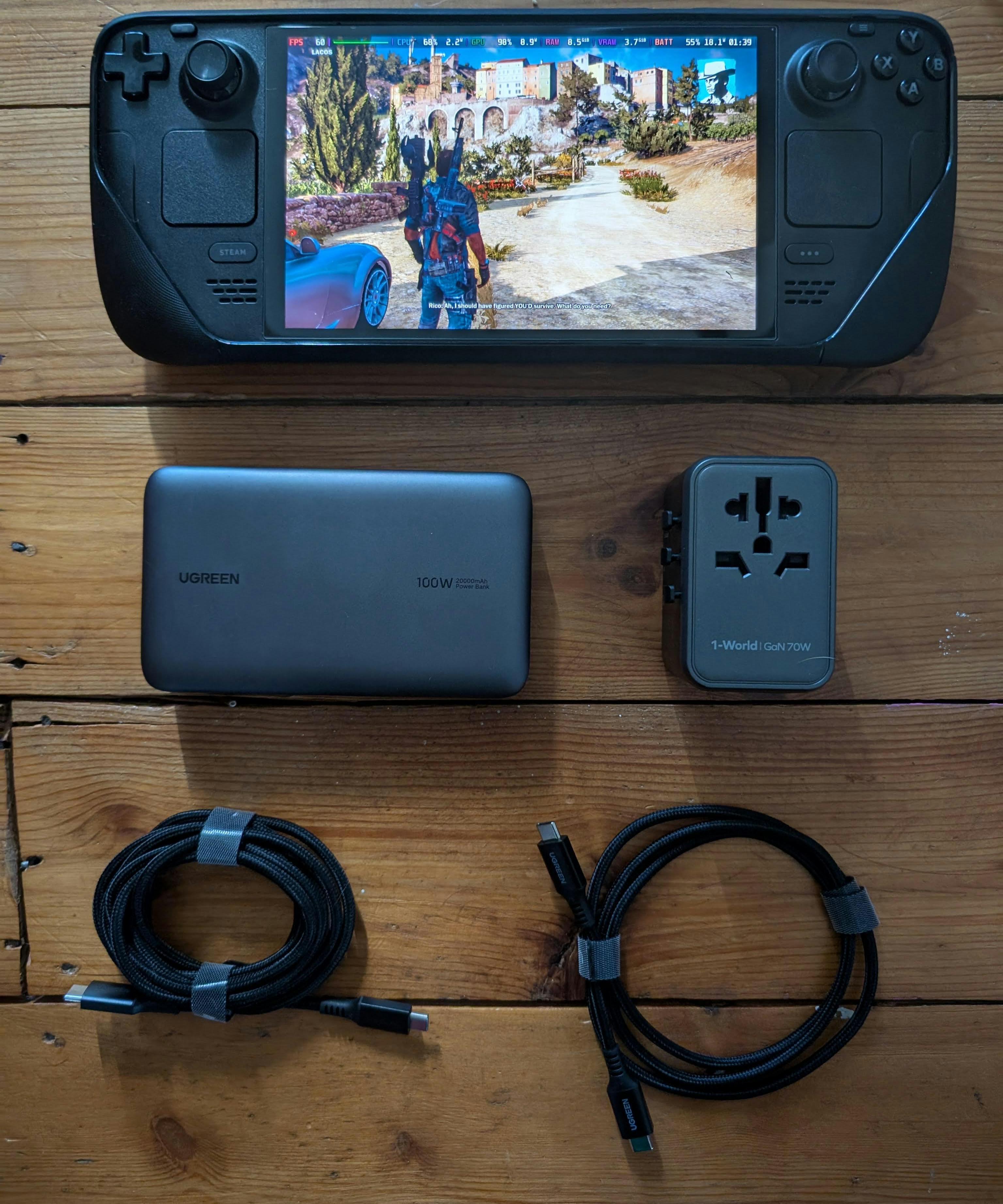 The items from the bag laid out on the floor - Steam Deck, charger, battery and 2 cables.