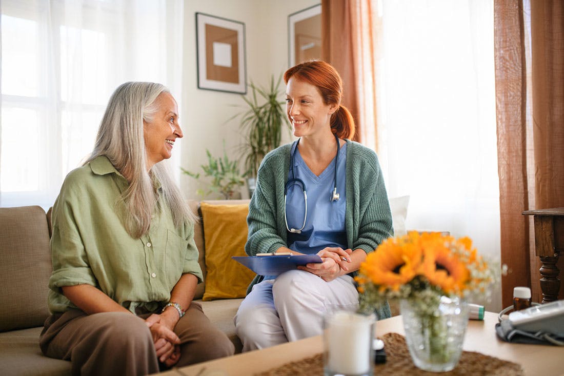 Elderly woman receiving care at home from health care worker