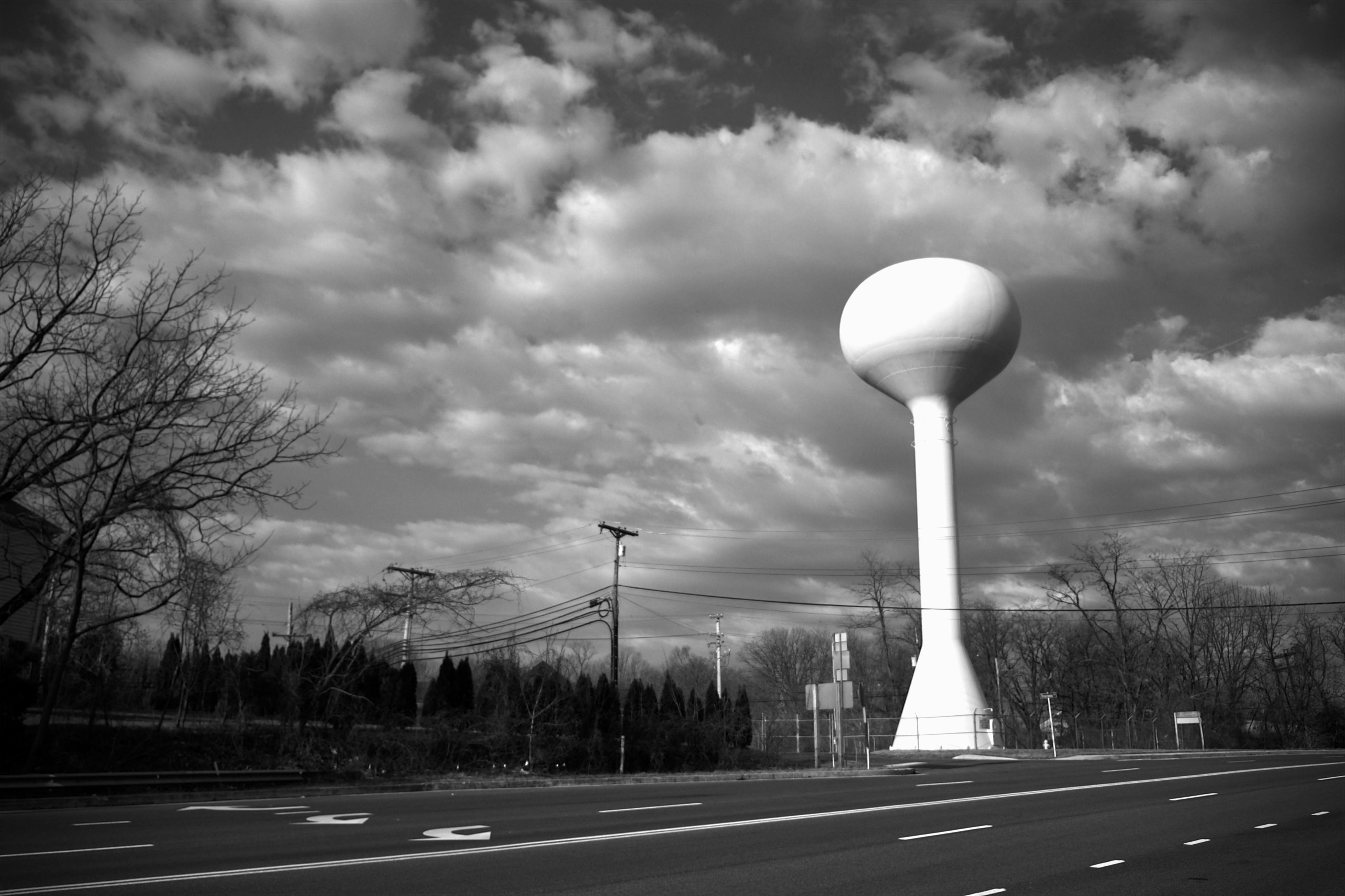 Black and white photo of a water tower against a cloudy sky