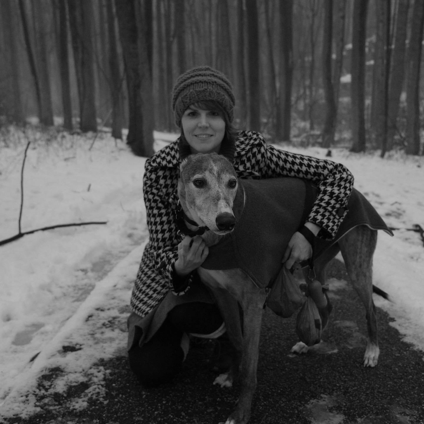 Jackie, posing with a young Kepler (our pet greyhound) on a snowy day in the woods.