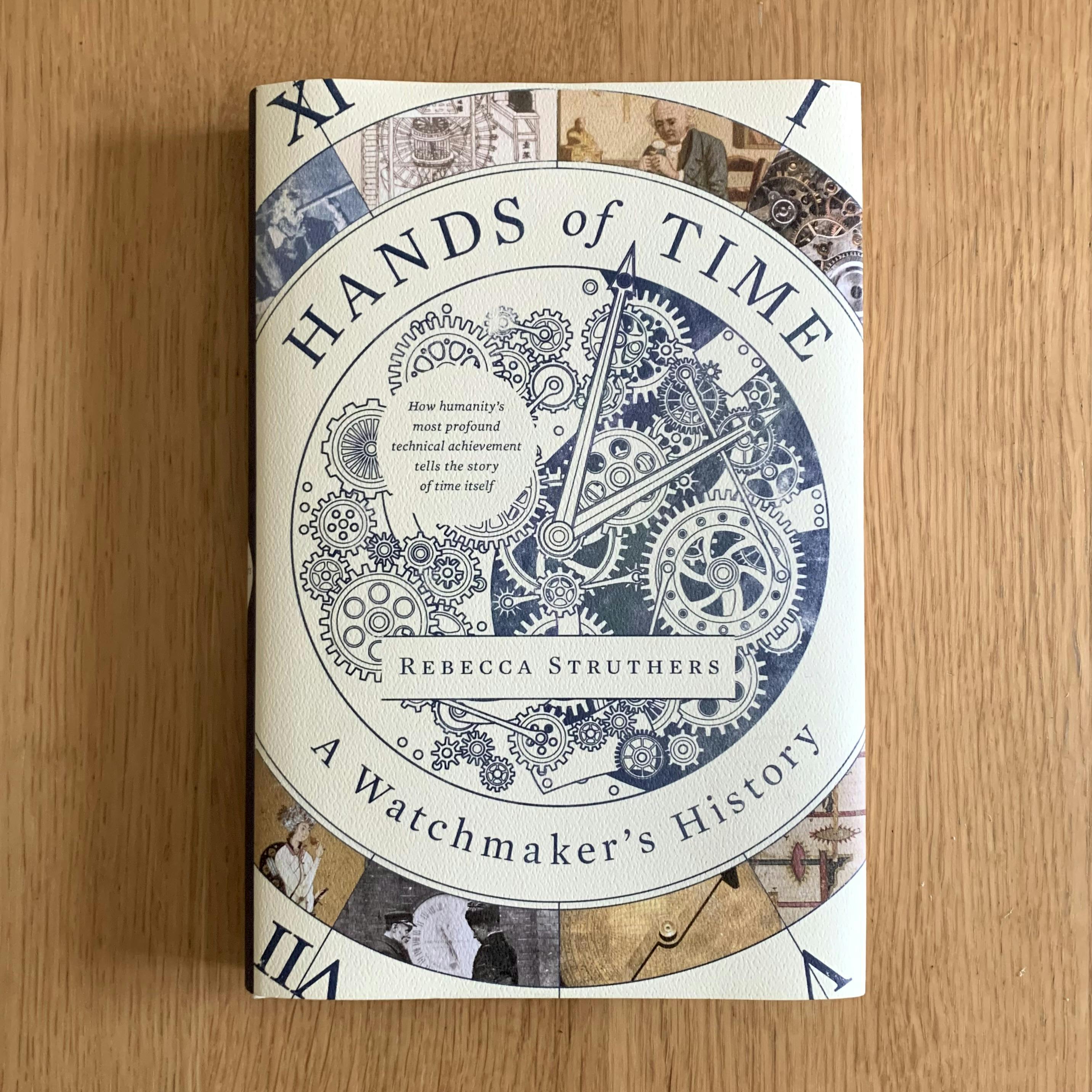 The cover of my copy of Rebecca Struthers’ Hands of Time: A Watchmaker’s History. The book, a hardcover edition, rests on a wooden surface.