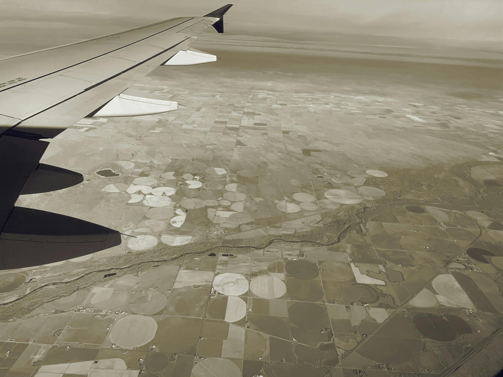 Photo from a plane window, showing irrigated, circular farm fields outside Denver
