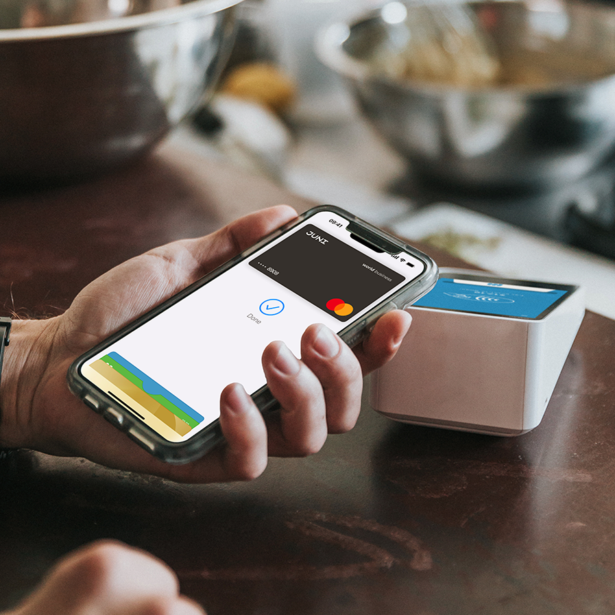 Hand holding IPhone and paying with Apple Pay