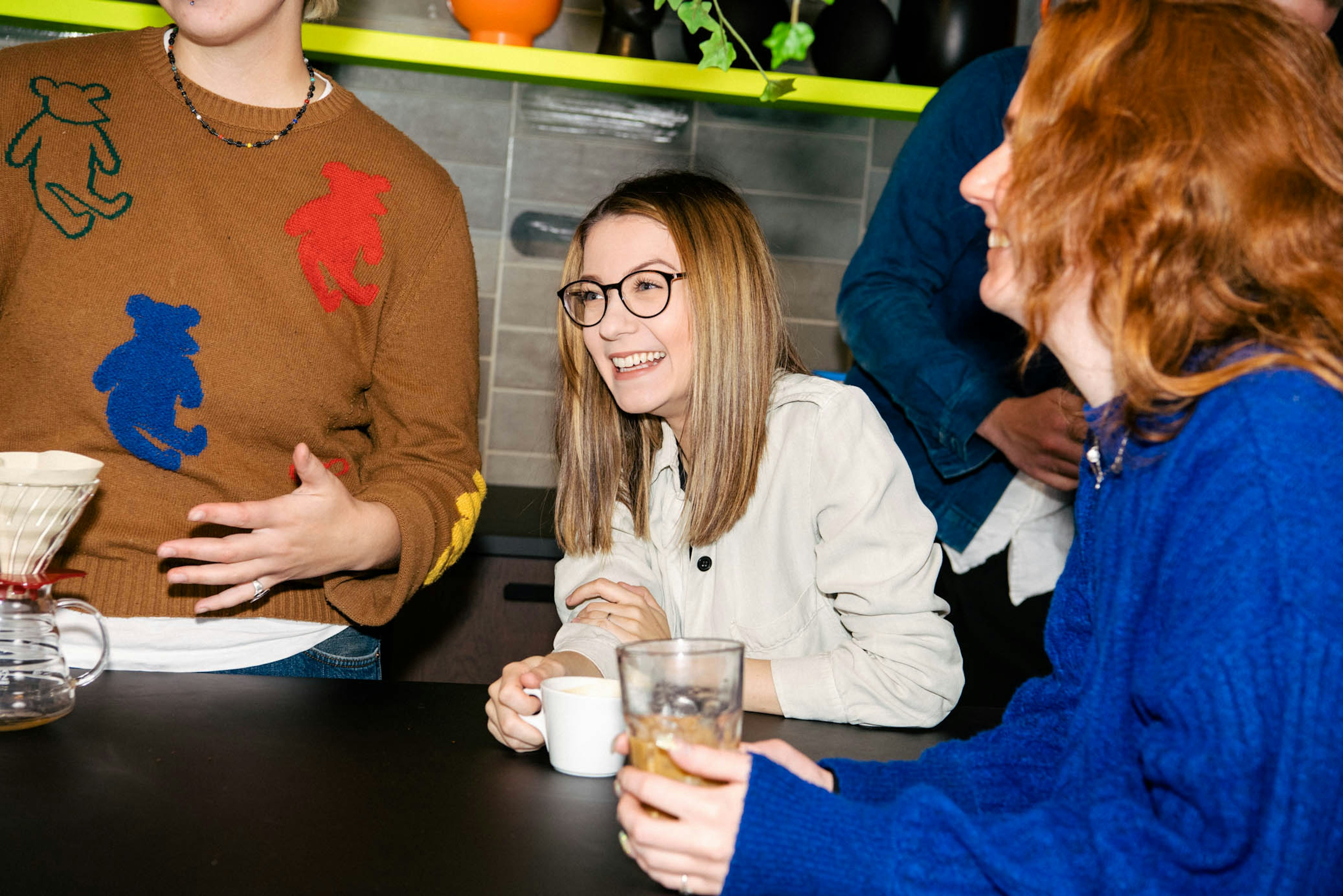 Þrír einstaklingar standa saman við borð í eldhúsi.
