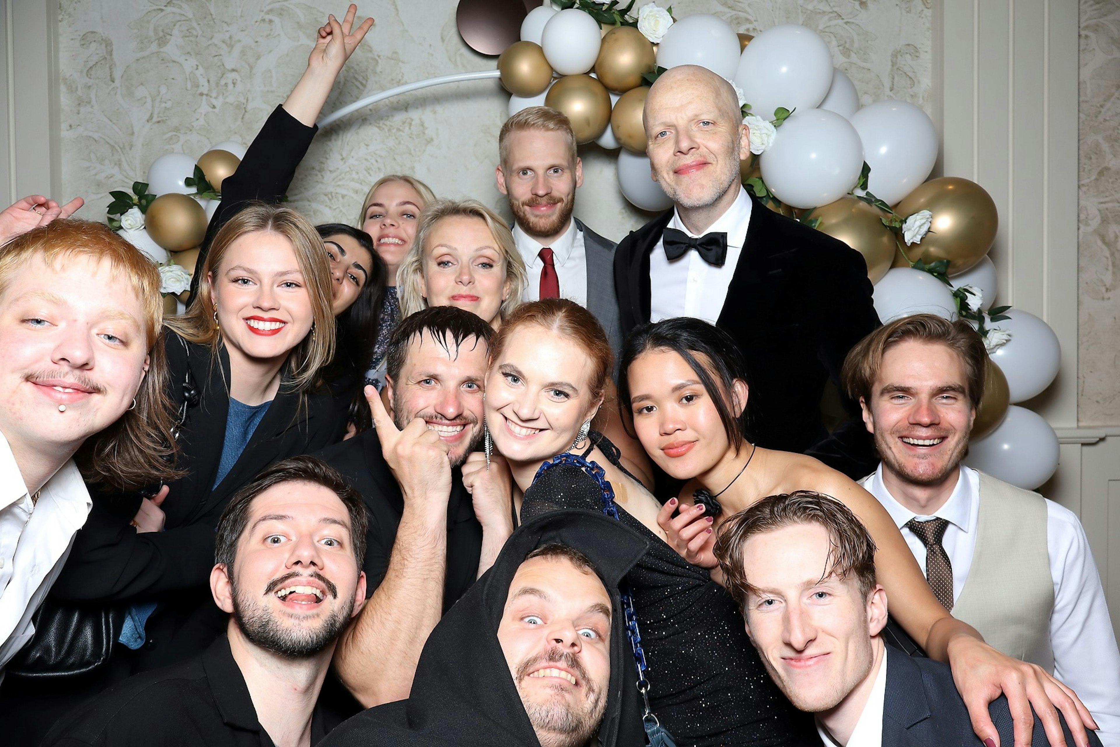 Gleðileg hópmynd á hátíðarhöldum, með brosandi fólki í formlegum klæðnaði.