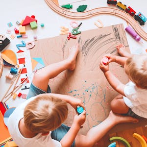 Kinder malen auf einem Pappkarton auf dem Boden mit offenen Farben