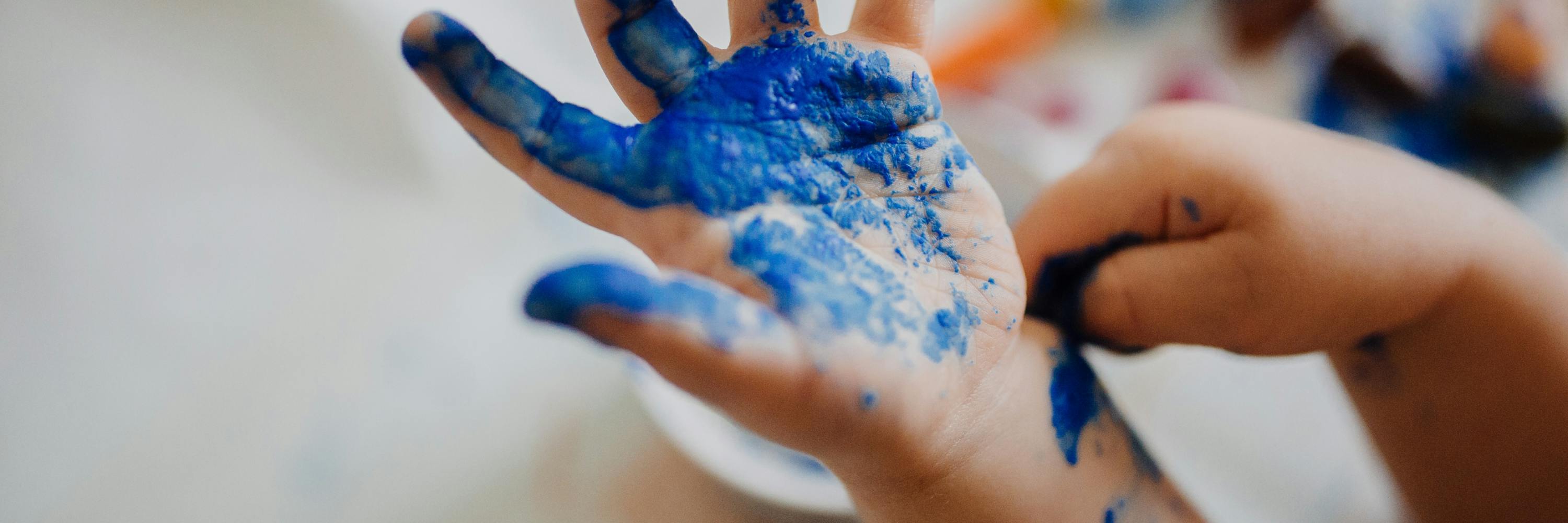 Kinderhand mit blauer Farbe besprenkelt