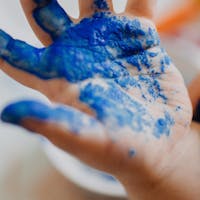 Kinderhand mit blauer Farbe besprenkelt