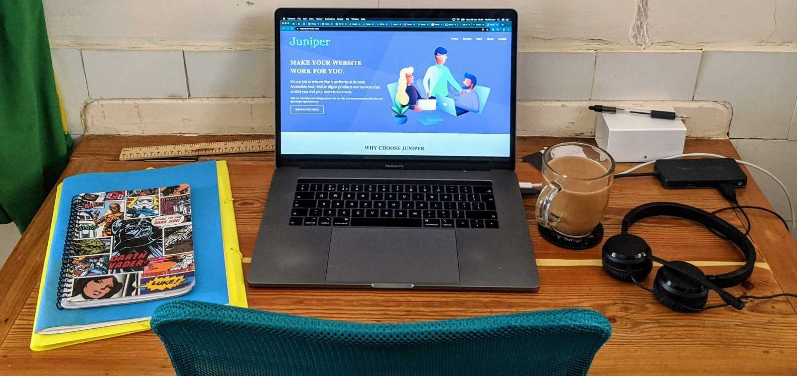 Photo of desk with laptop, coffee and headphones