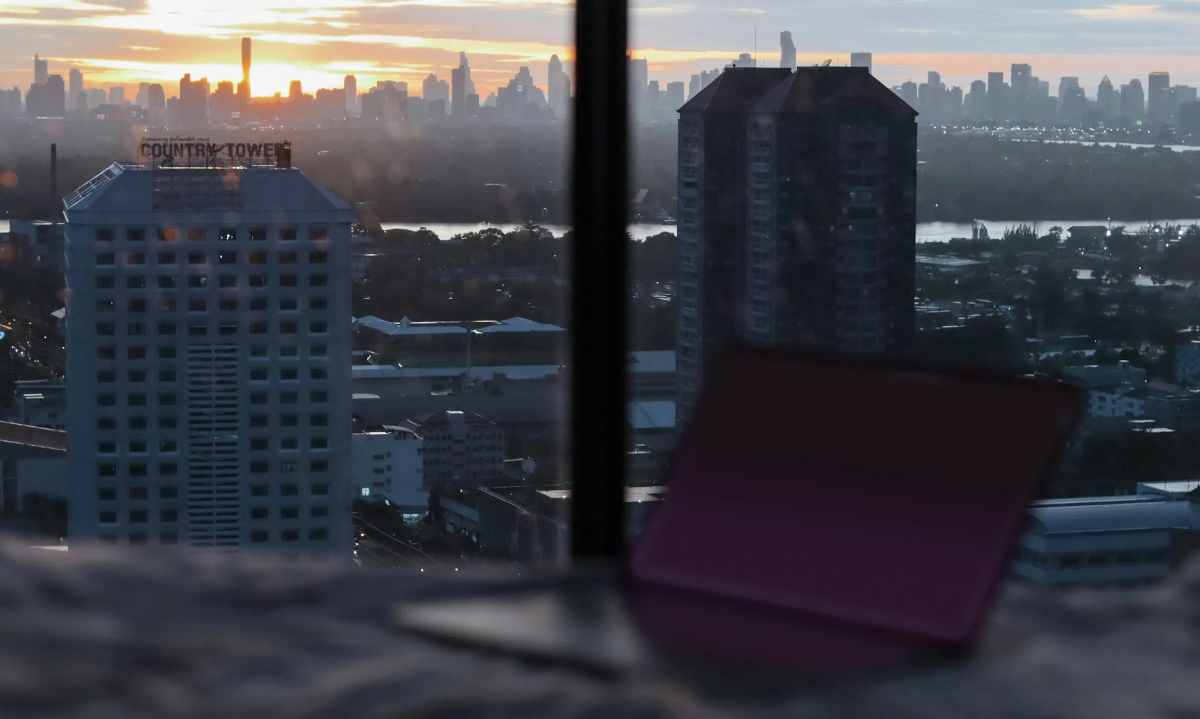 laptop open next to window with city view