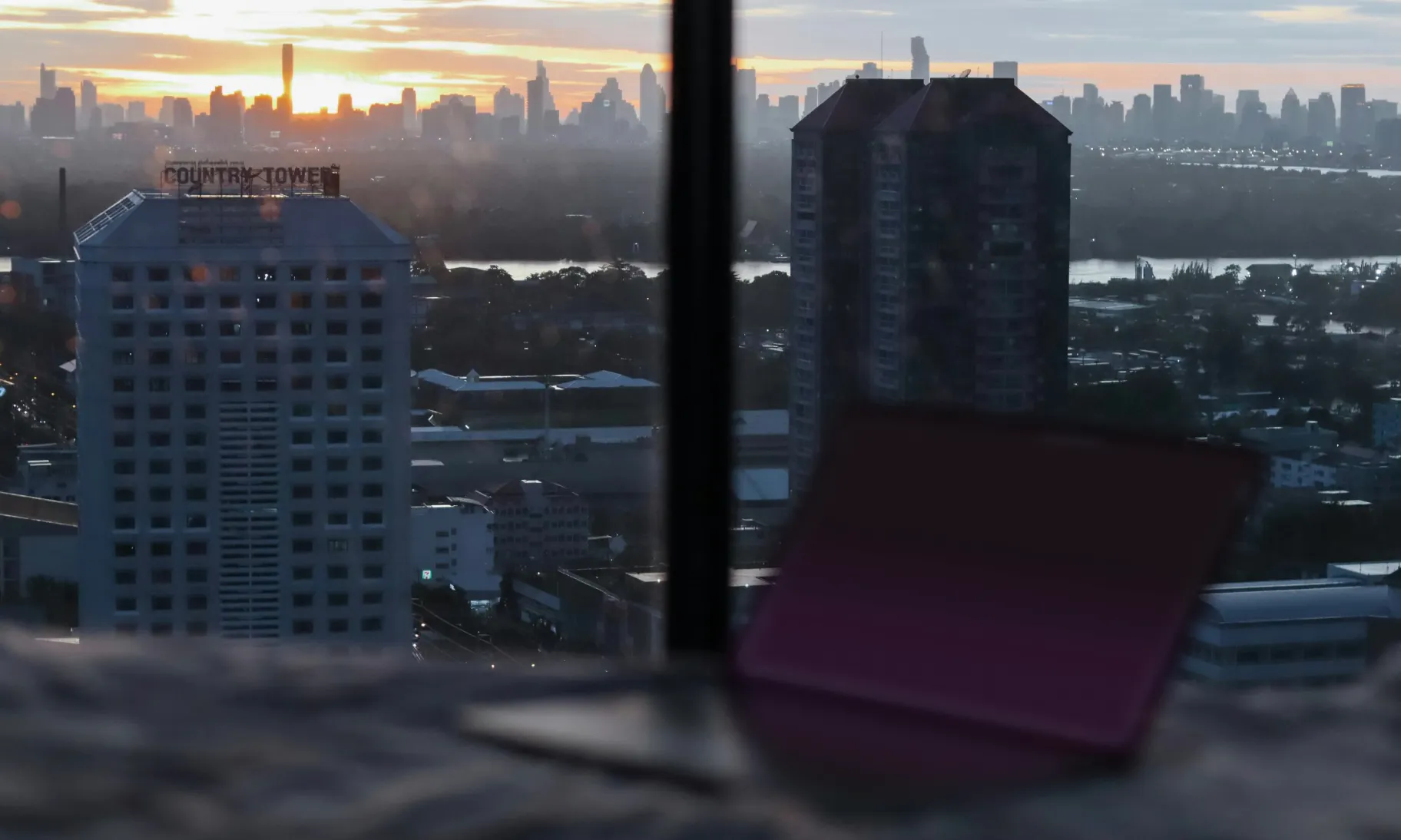 laptop open next to window with city view