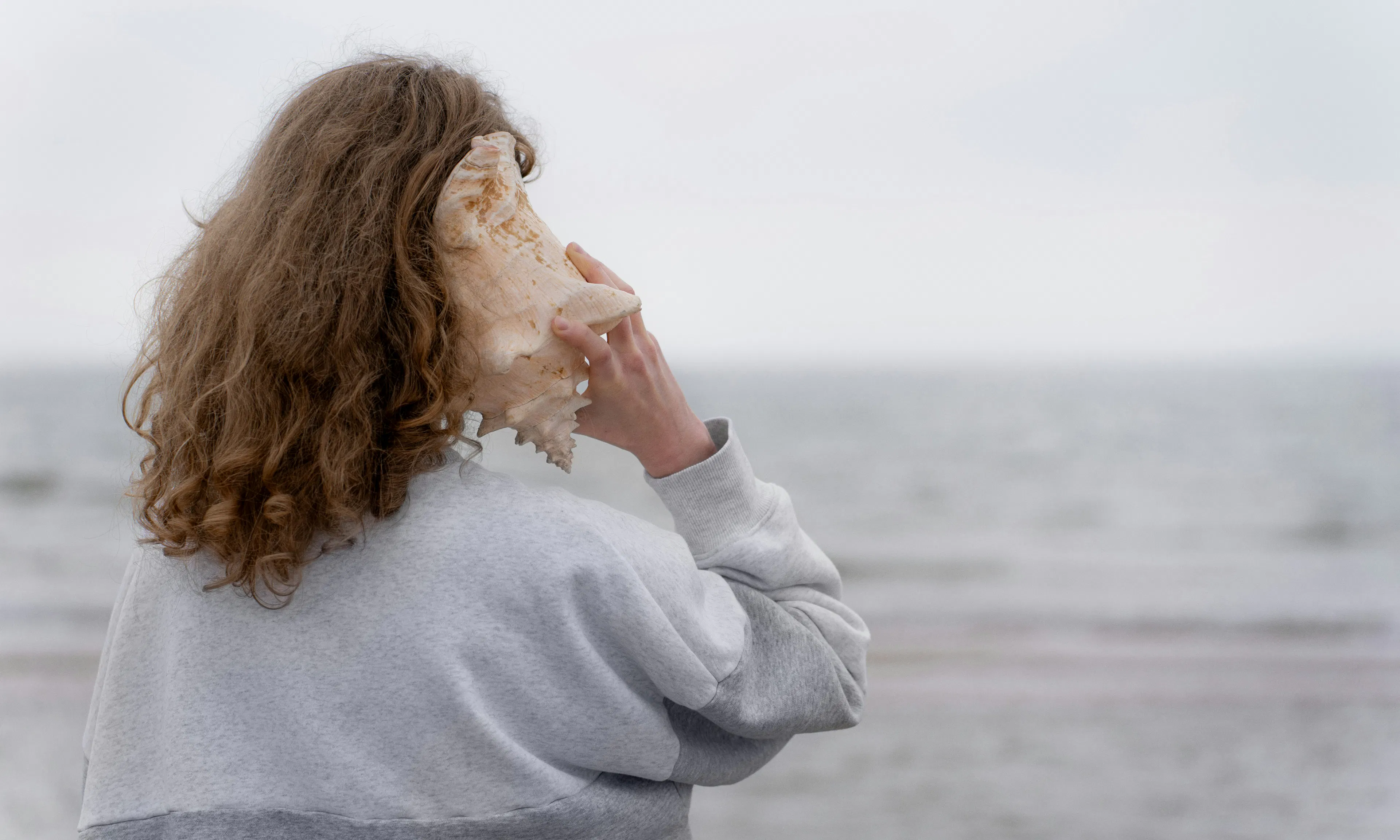 woman holds conch to her ear
