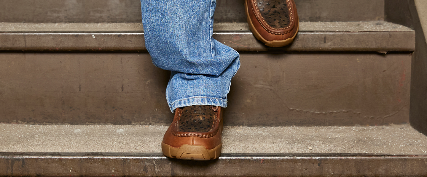 Un hombre en jeans baja las escaleras usando los Justin Light Duty Casuals.