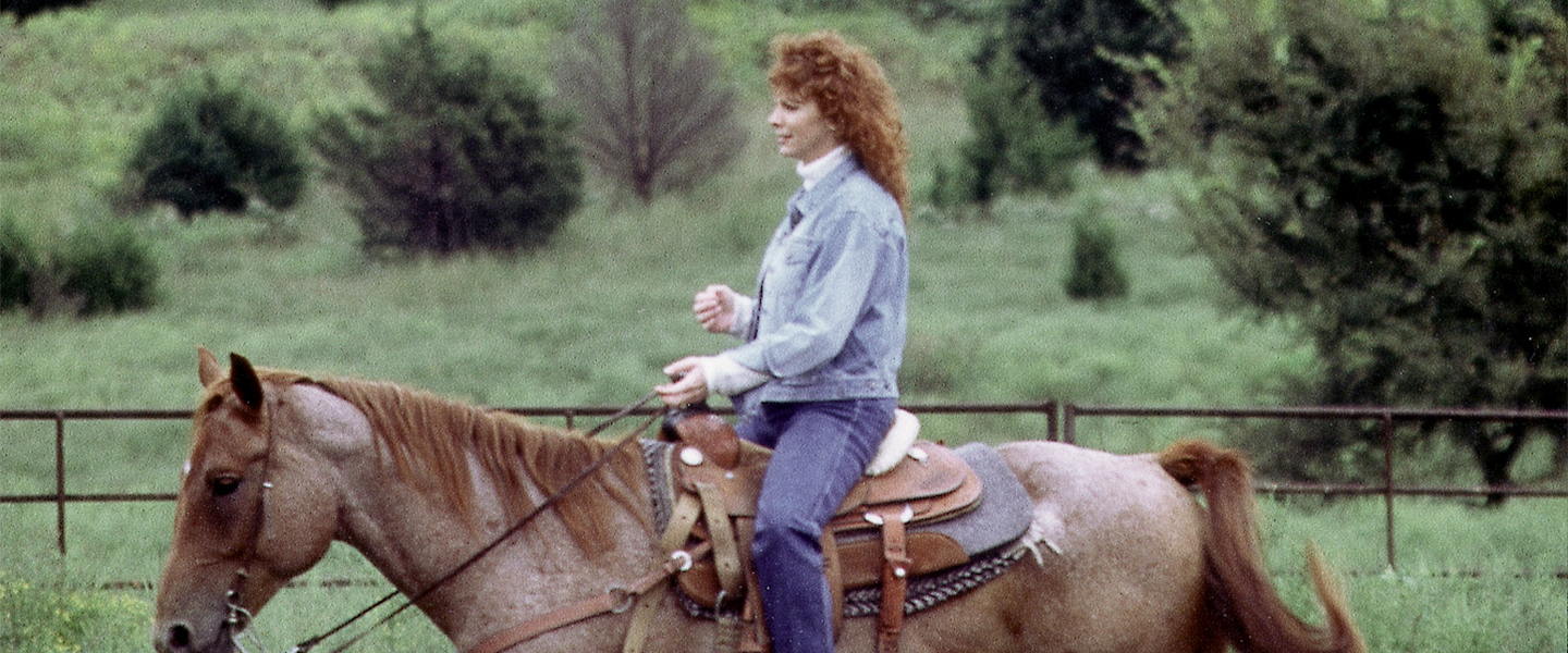 A picture of Reba McEntire riding her horse.