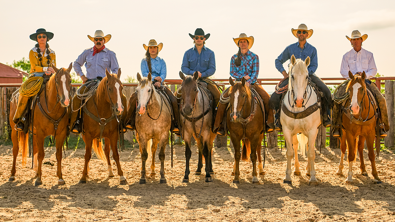 A group of cowboys and cowgirls sitting on their horses in an arena, outdoors.