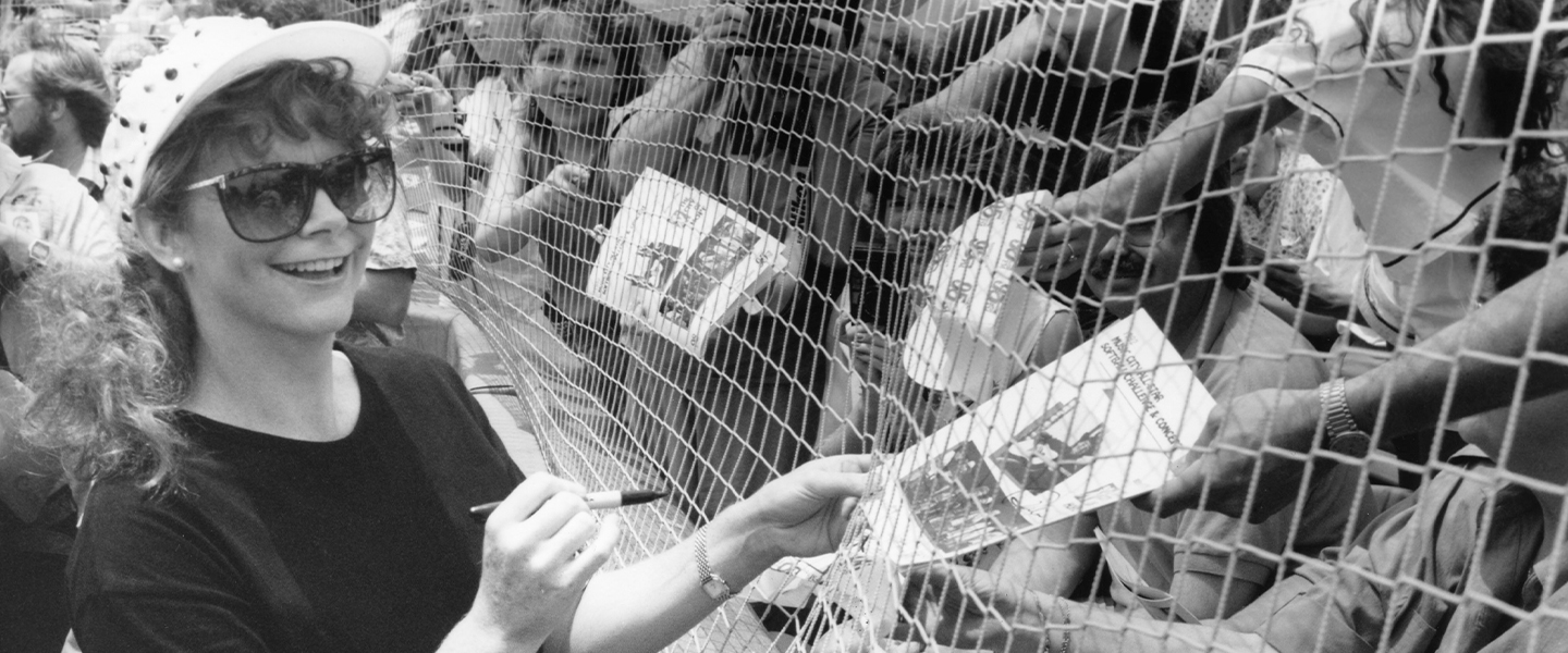 A black and white picture of Reba McEntire signing autographs.