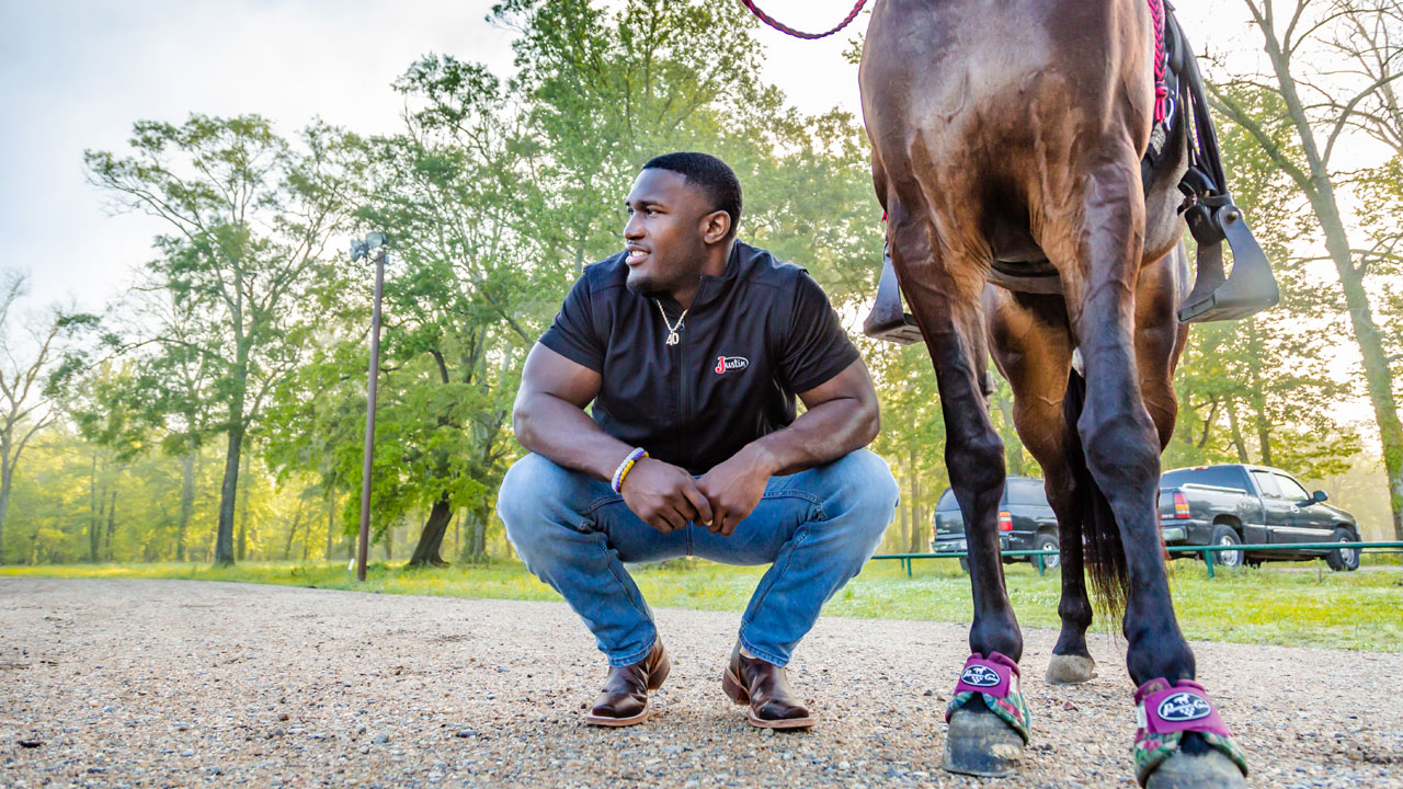Devin White kneeling next to his horse.