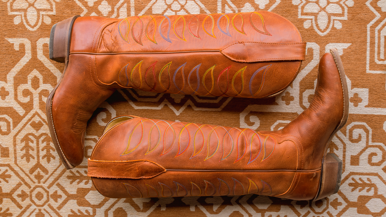 A pair of vintage brown boots laying flat on a textured carpet.