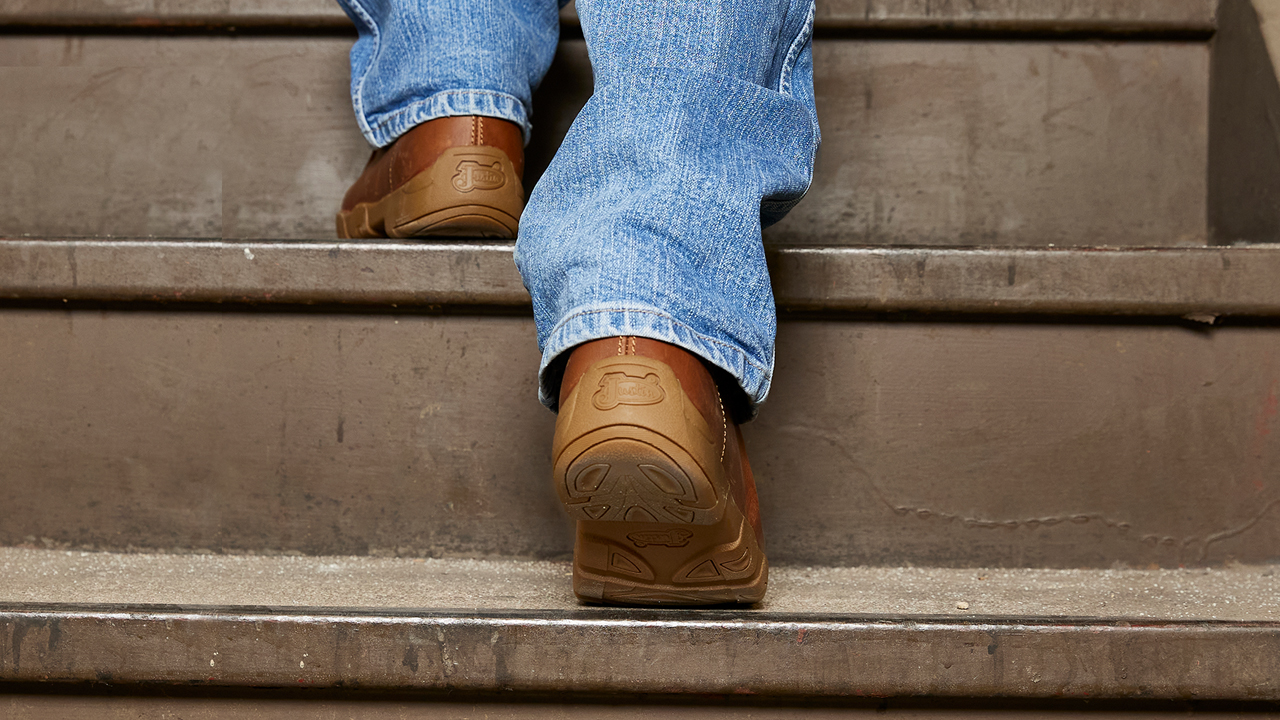 Un hombre en jeans sube las escaleras usando las Justin Light Duty Casuals.