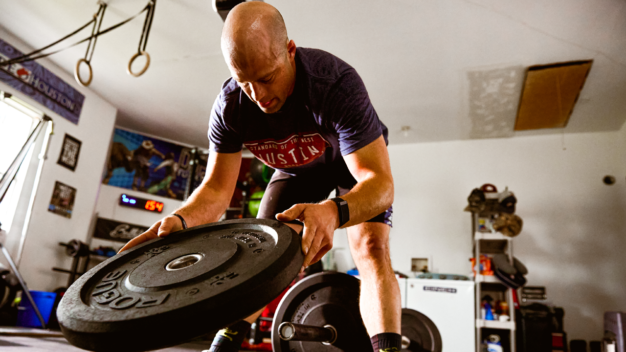PRCA Bullfighter Dusty Tuckness adding more weight to a barbell during a workout.