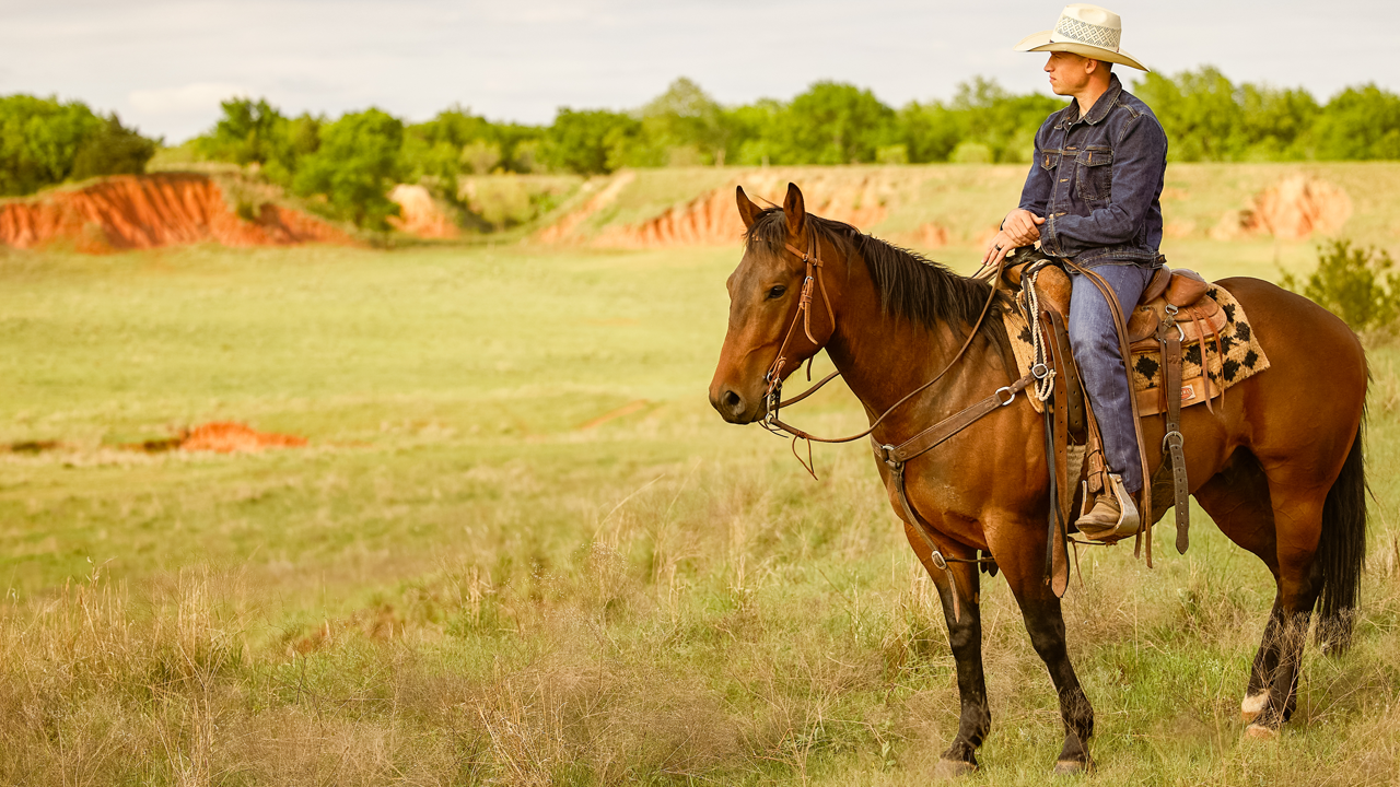 Professional Bullfighter Cody Webster riding a horse in a pasture on his ranch.