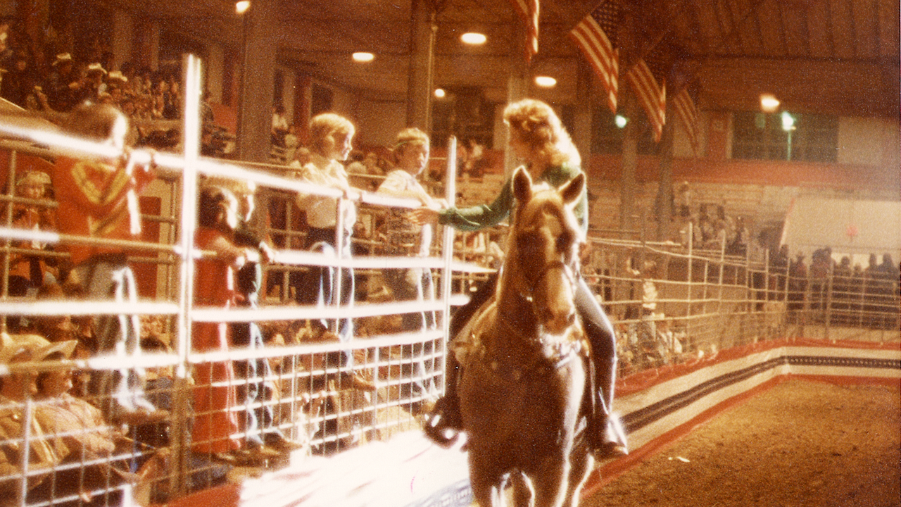 Young Reba interacting with fans at a rodeo.