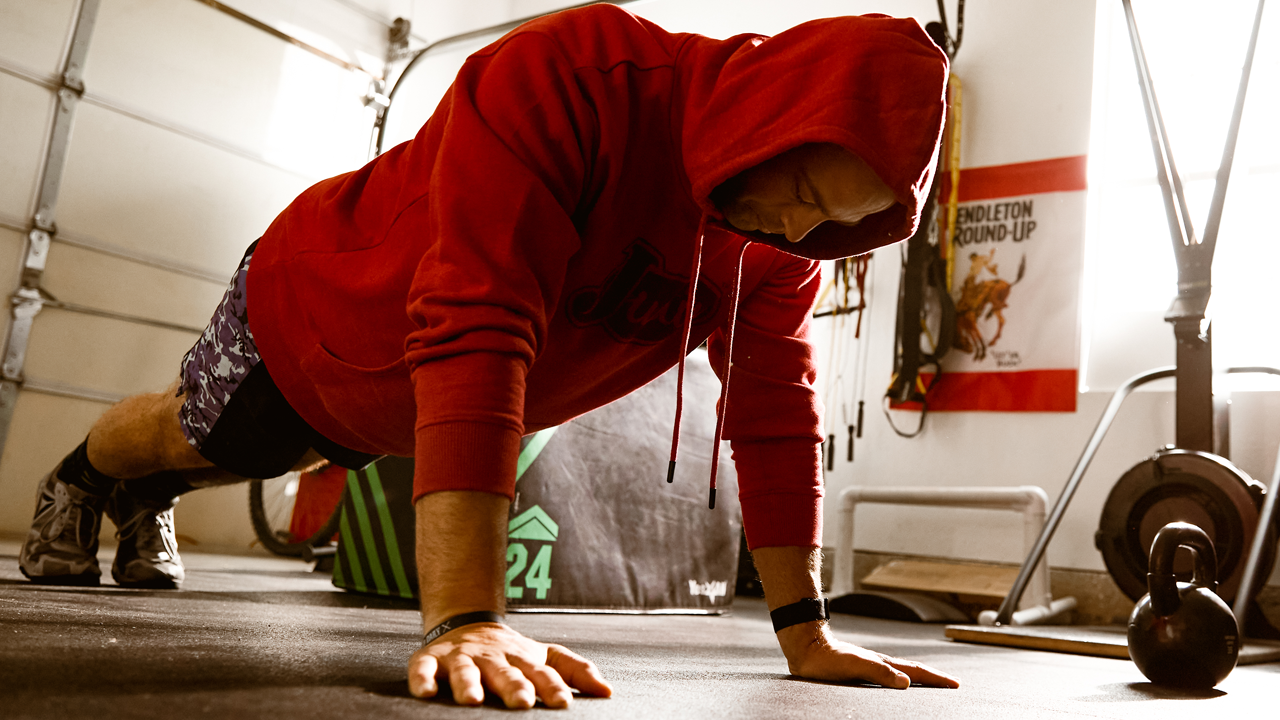 PRCA Bullfighter Dusty Tuckness doing pushups in a hooded sweatshirt during a workout.