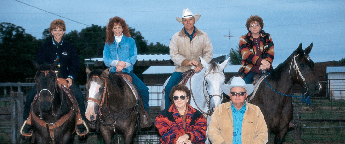 A picture of the McEntire family posing for a picture with their horses.