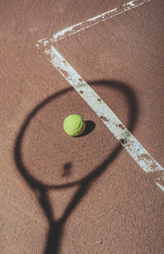 Tennis racket shadow and tennis ball on court