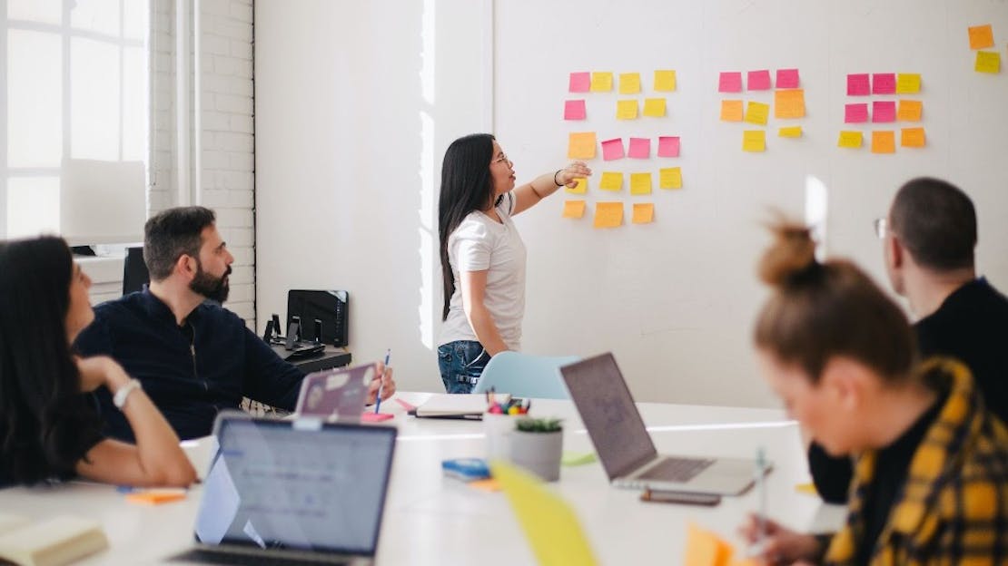 People working looking at a board with post its