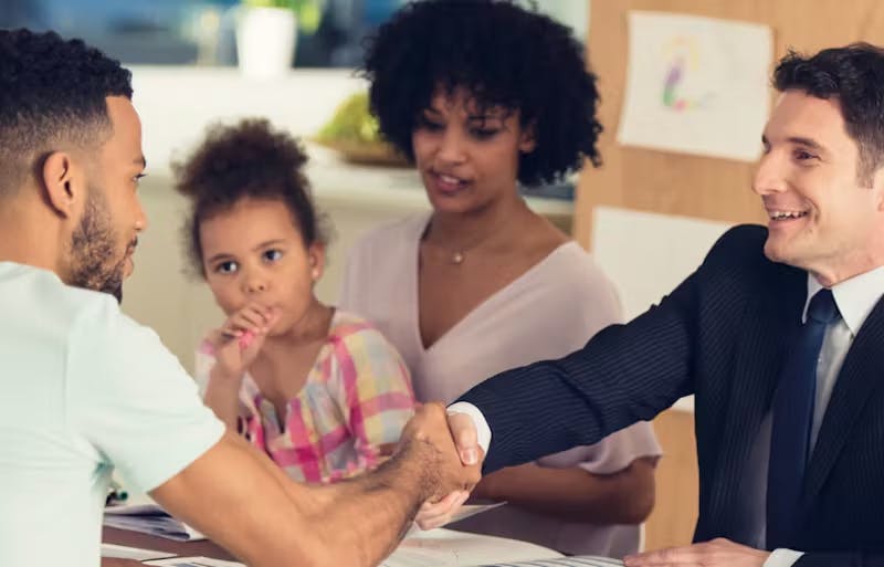 2 people shaking hands and another holding a child