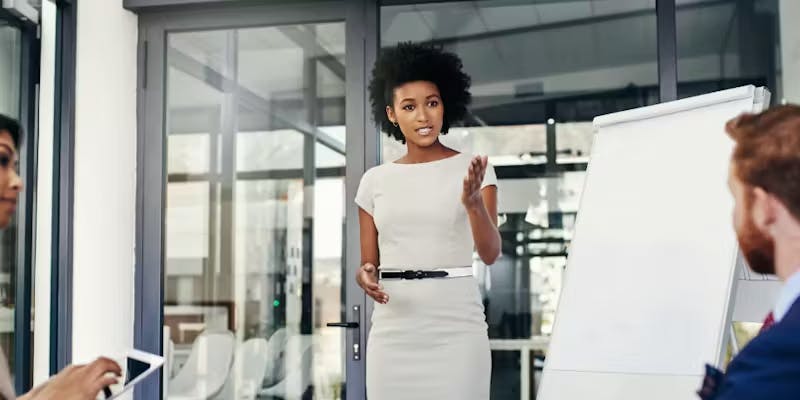 A woman in a white dress next to a white board