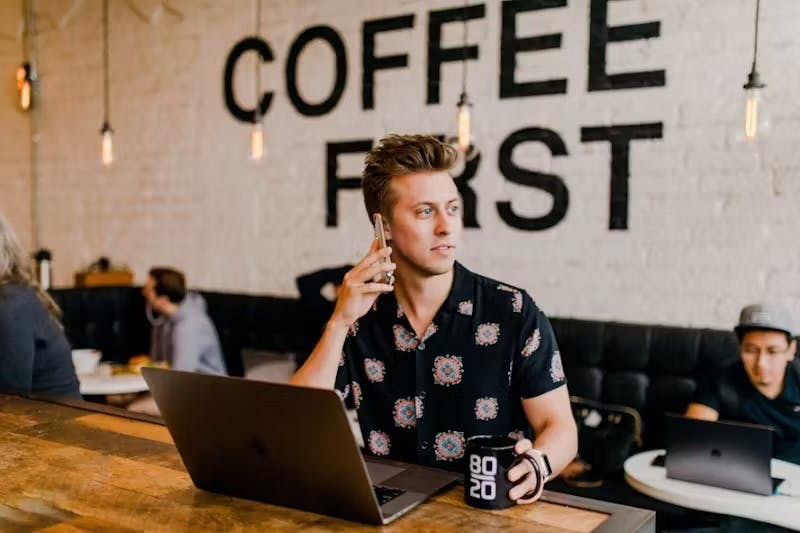 Man over the phone with his laptop and a coffee