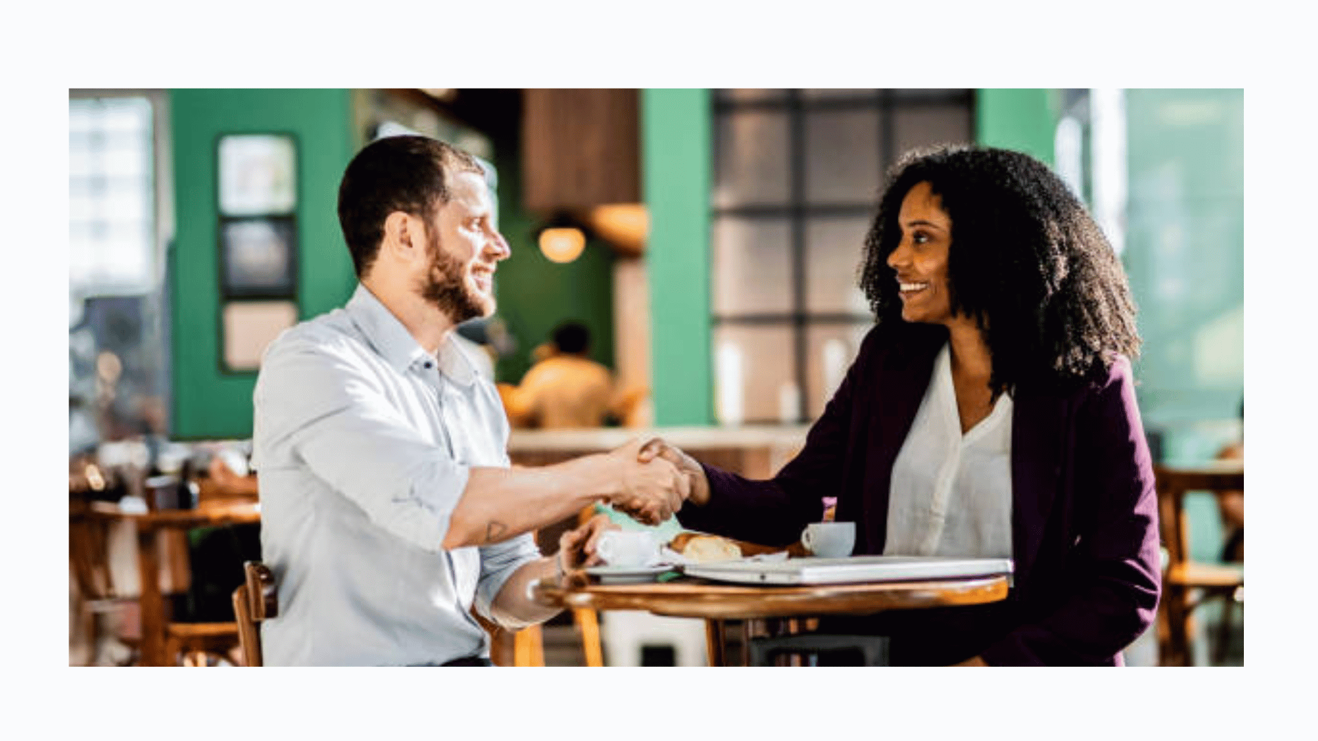 Two professionals shaking hands and smiling at a business event