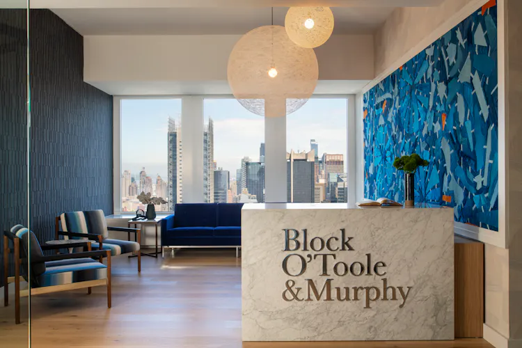 Luxury office reception at One Penn Plaza by K.A. Murphy Interiors with custom millwork, marble reception desk, contemporary furnishings, and skyline views.