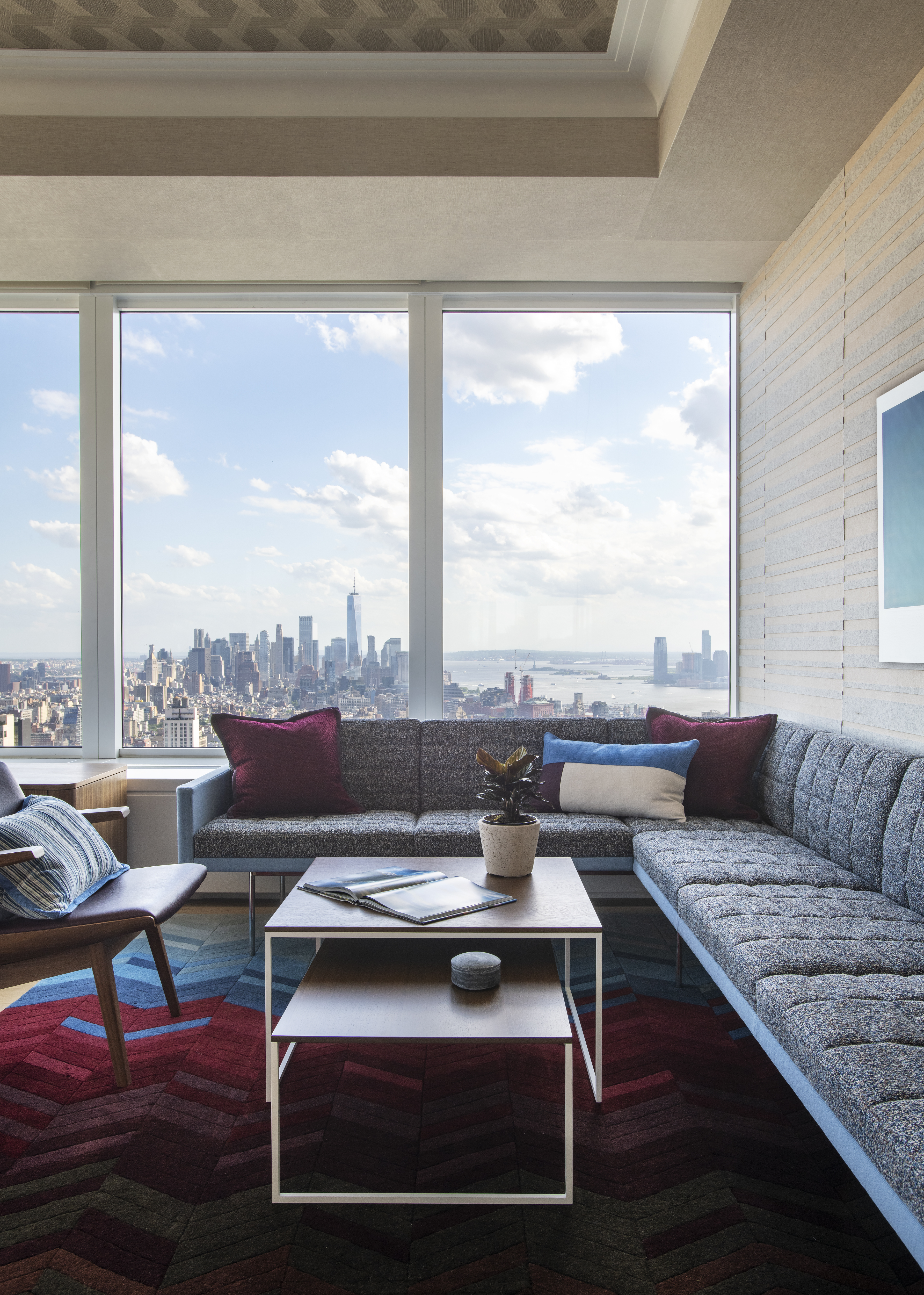 Luxury office lounge at One Penn Plaza designed by K.A. Murphy Interiors with custom furnishings, layered textures, and expansive Manhattan skyline views.